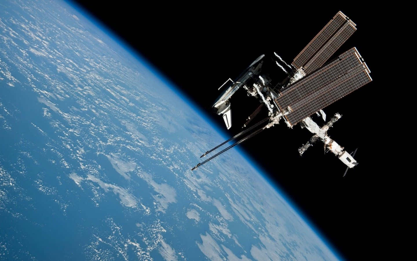 Satellite 桌布 壁紙 — 一個詳細的太空站繞地球軌道運行，展示藍色海洋、白色雲朵和遠方的黑色虛空。