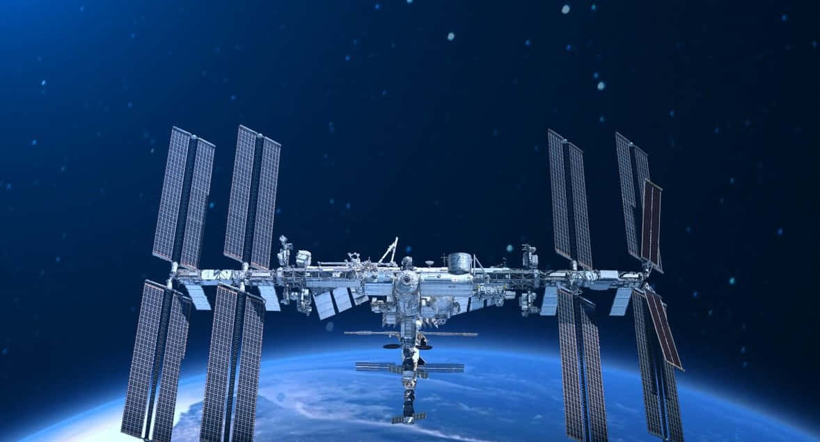 International Space Station 桌布 壁紙 — 一個詳細的太空站繞地球運行，太陽能板在繁星點點的藍色背景下展開。