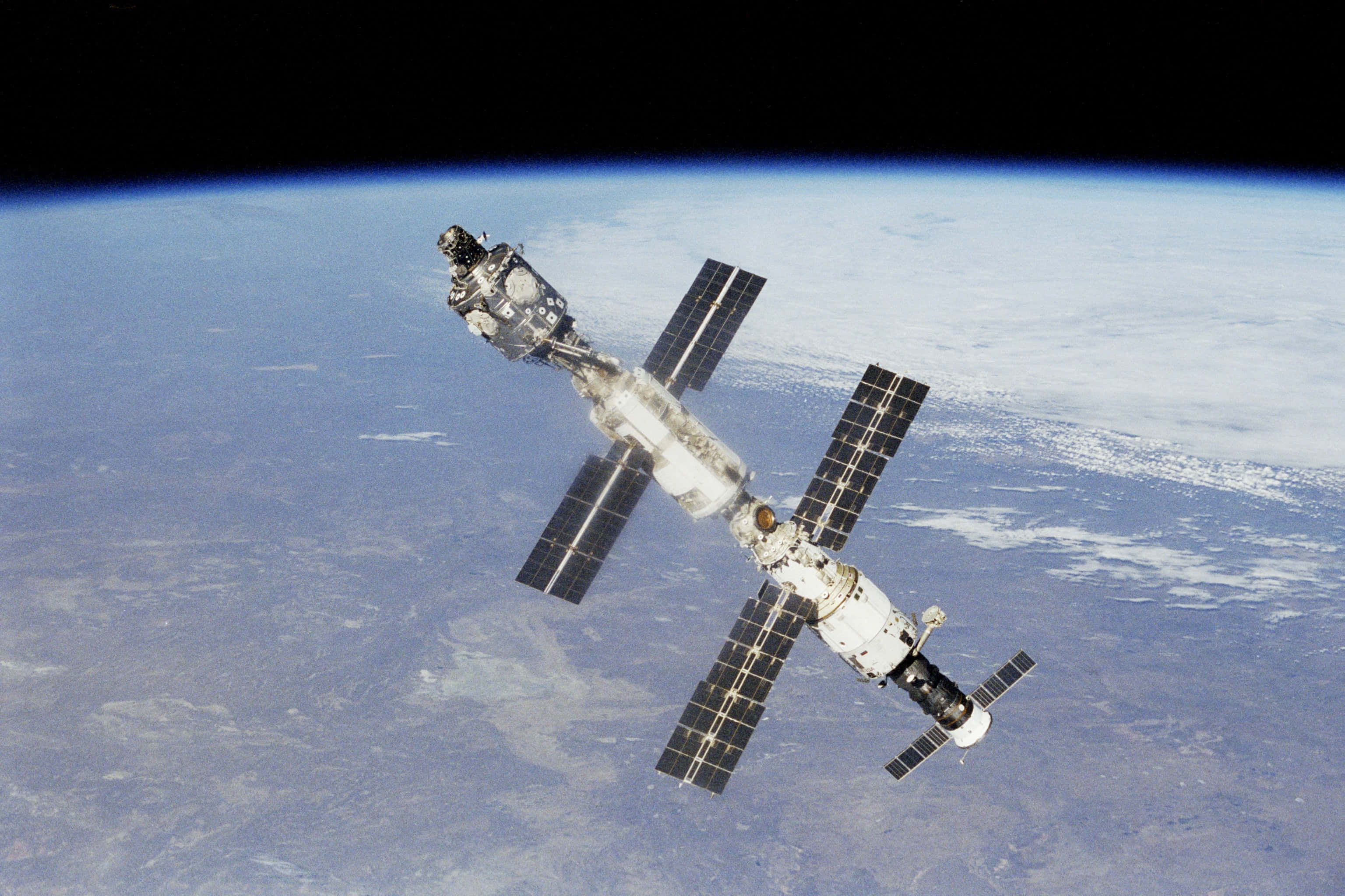 Iss 桌布 壁紙 — 一個詳細的太空站繞地球運行，太陽能板在太空的黑暗中展開。