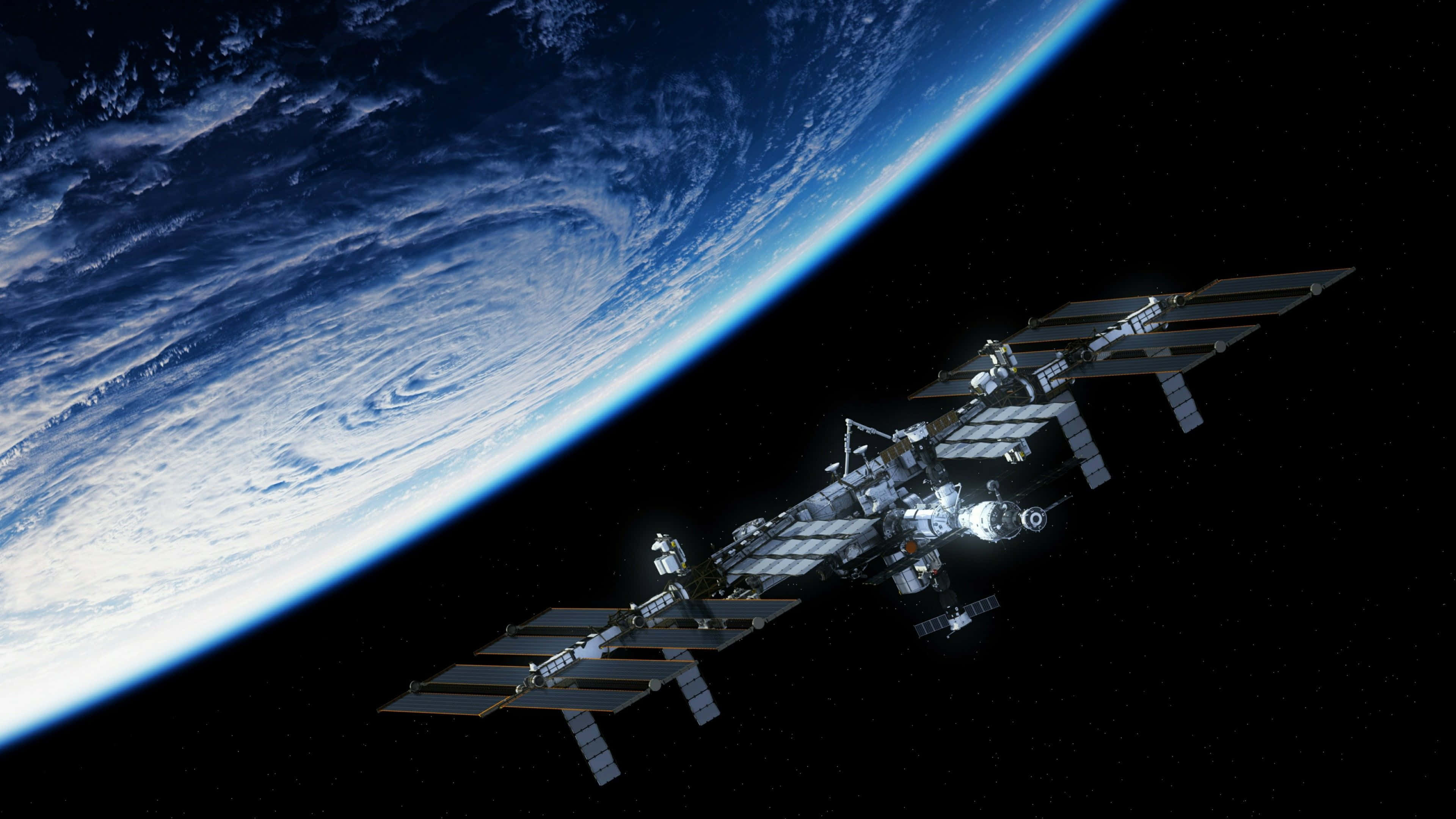 Iss 桌布 壁紙 — 一個詳細的太空站繞地球運行，展示出旋轉的雲層和藍色海洋，背景是黑色的太空虛空。