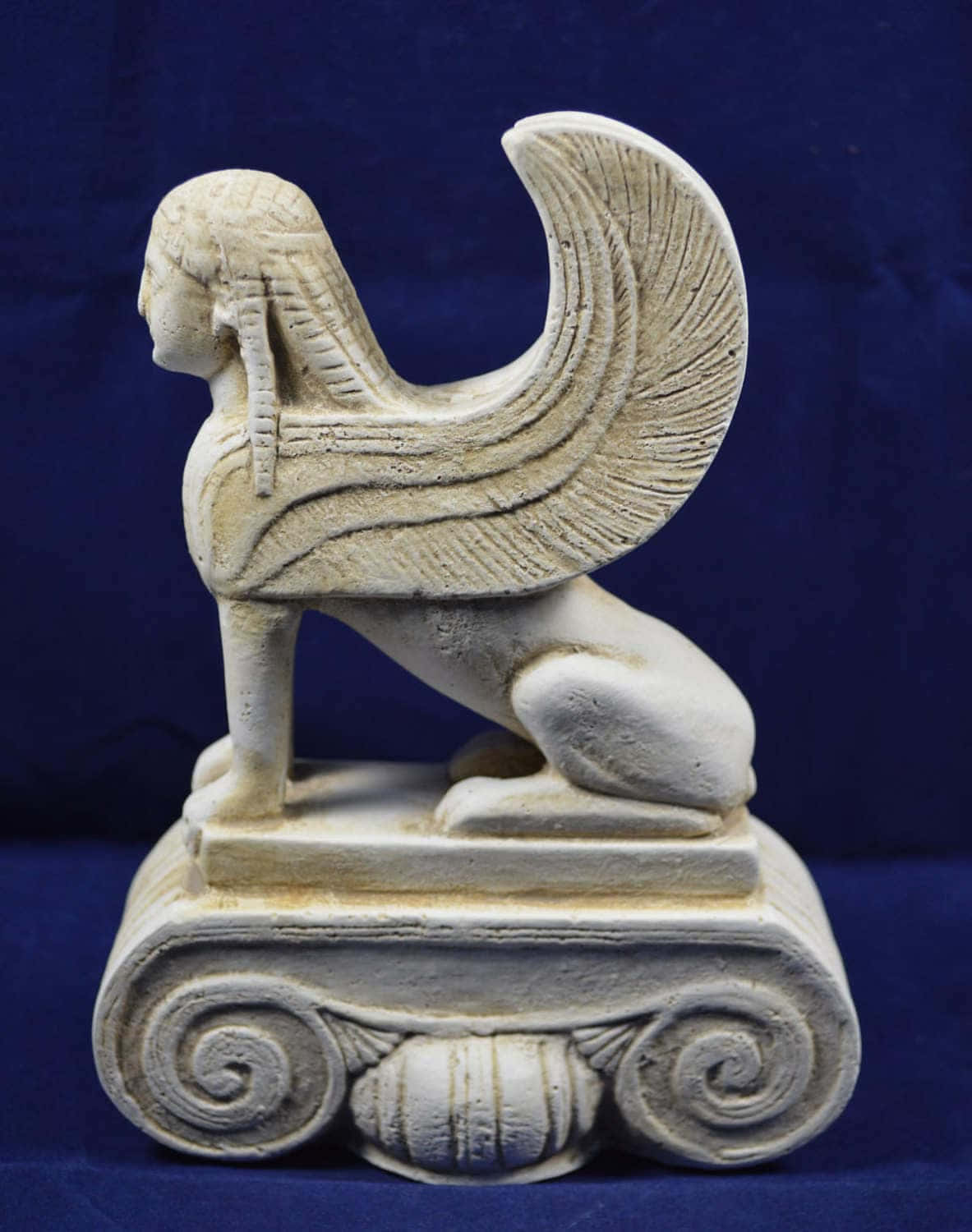 Mystical Artifacts 桌布 壁紙 — 一個詳細的奶油色獅身人面像雕像，有人頭和獅身，坐在裝飾底座上，背景是深藍色。