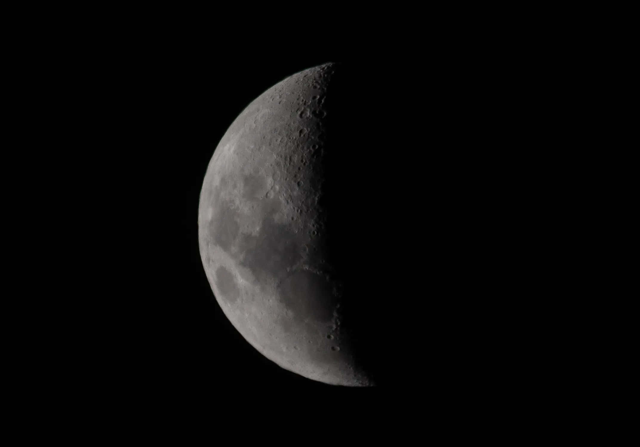 Half Moon 桌布 壁紙 — 一個詳細的彎月，可見隕石坑和陰影，背景是漆黑的天空。