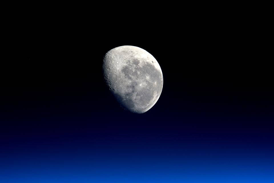 nasa 美學 桌布 壁紙 — 一個詳細的彎月懸掛在漸變藍色夜空中，在深邃的黑色背景下展示隕石坑和月球地形。