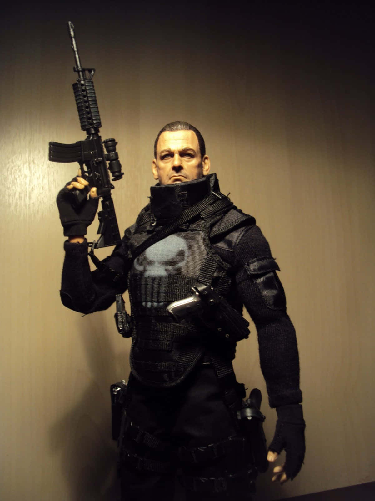Ray Stevenson 桌布 壁紙 — 一個詳細的懲罰者動作人偶，身穿全套戰術裝備，手持突擊步槍靠著素牆。