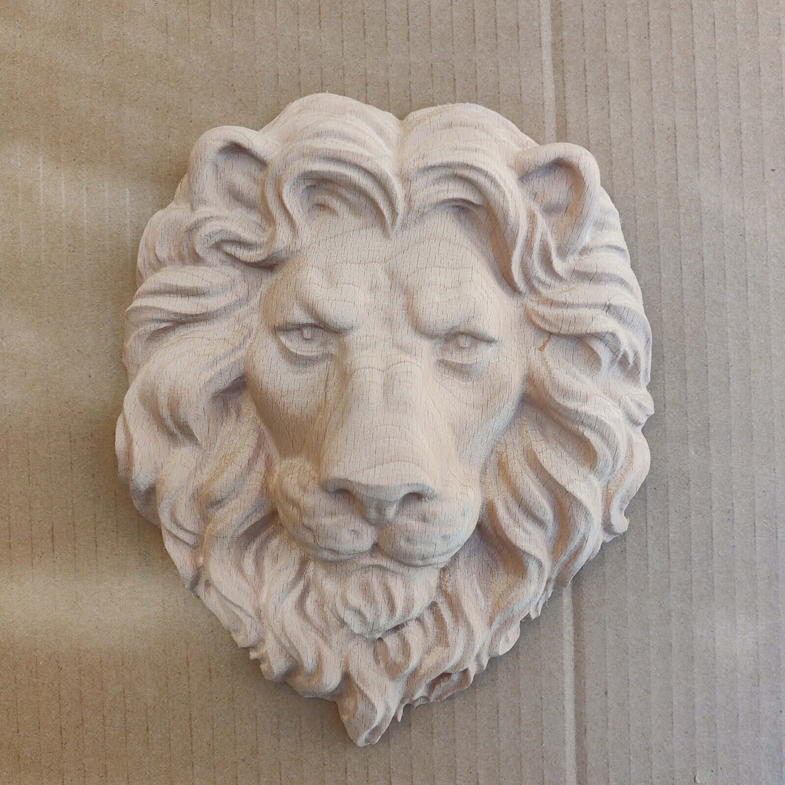 Lion Head 桌布 壁紙 — 一個詳細的木雕獅子頭，帶有流動的鬃毛，安裝在淺色木鑲板牆上。