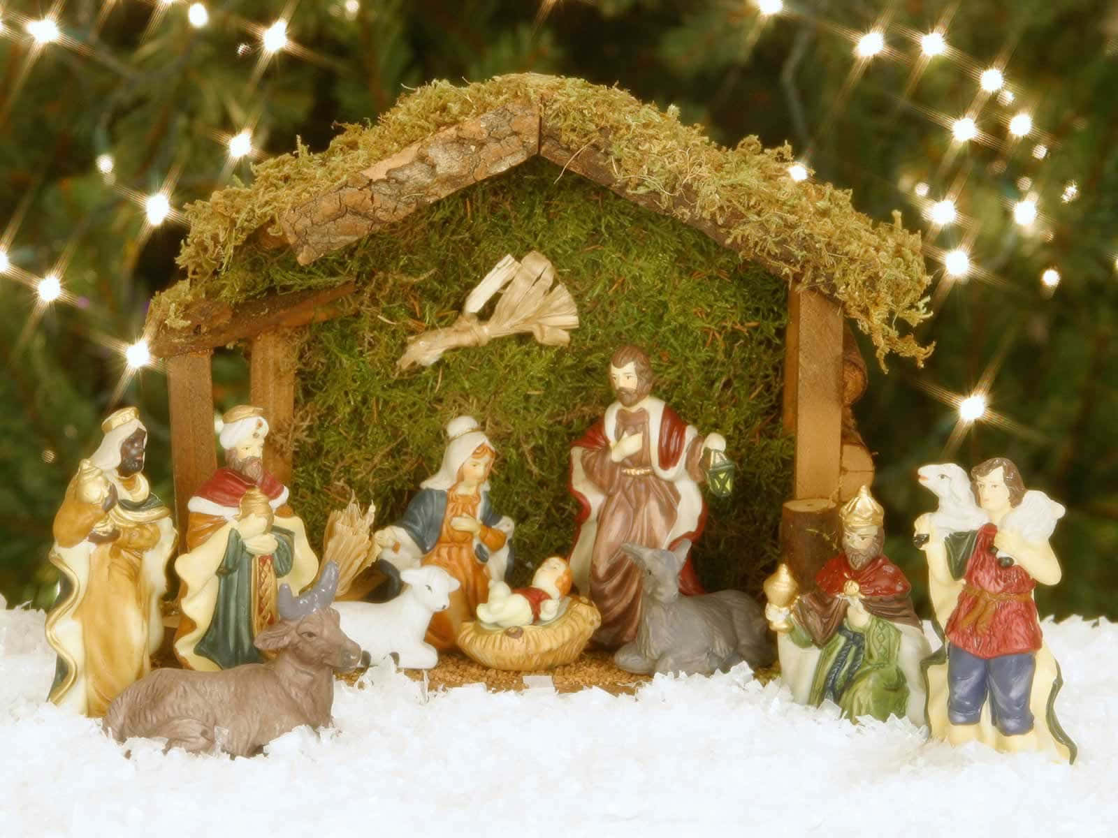 Nativity 桌布 壁紙 — 一個詳細的耶穌誕生場景，有瑪利亞、約瑟、嬰兒耶穌、牧羊人和動物的雕像，位於長滿青苔的屋頂下，背景有閃爍的仙女燈。