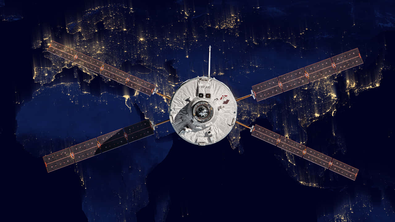 Space Debris 桌布 壁紙 — 一個詳細的衛星在夜間繞地球運行，其太陽能電池板在下方發光的城市景觀上空展開。