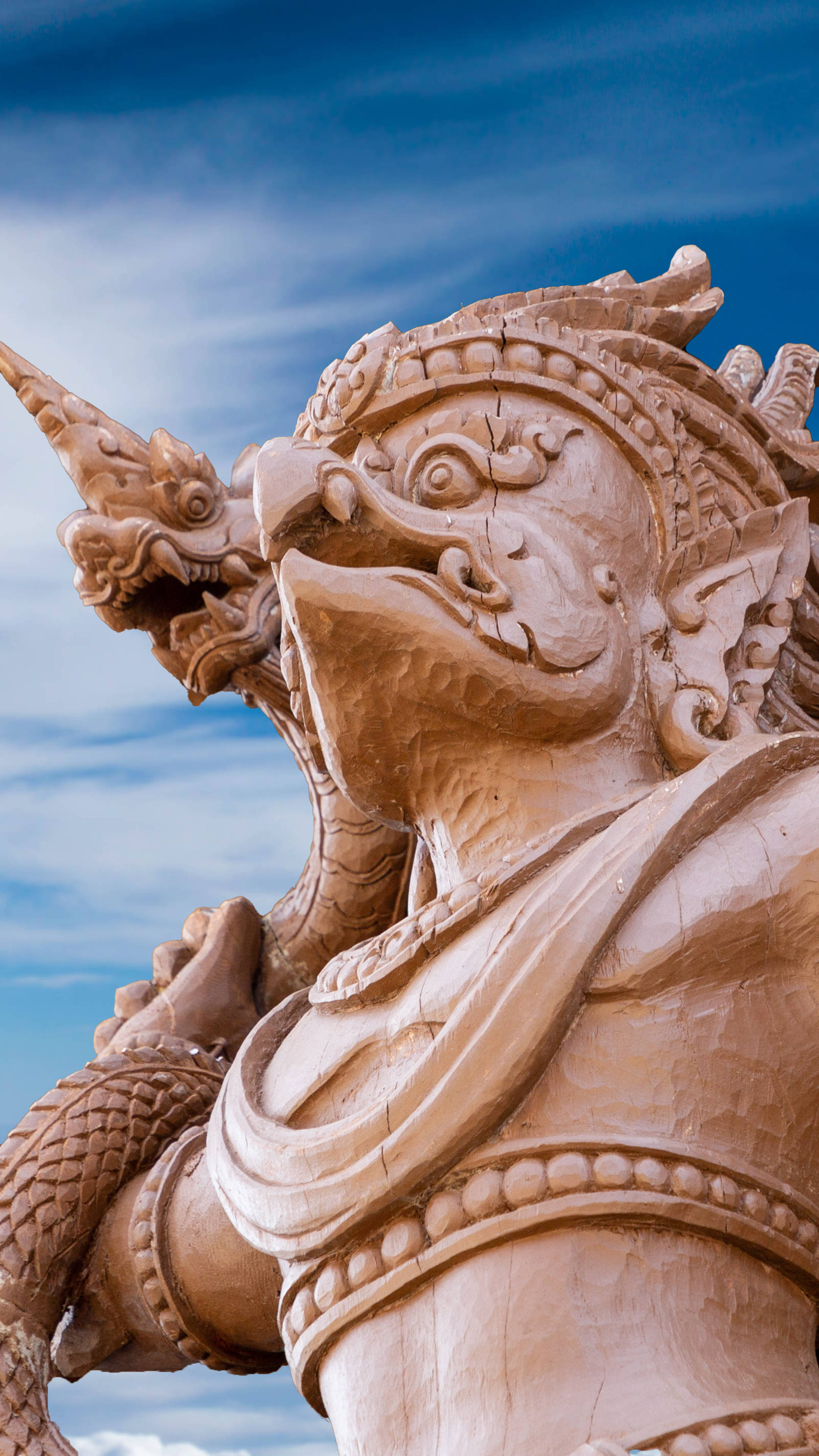 Statue Aesthetic 桌布 壁紙 — 一個詳細的赤陶雕像，描繪神話生物，有龍頭和華麗盔甲，背景是明亮的藍天。