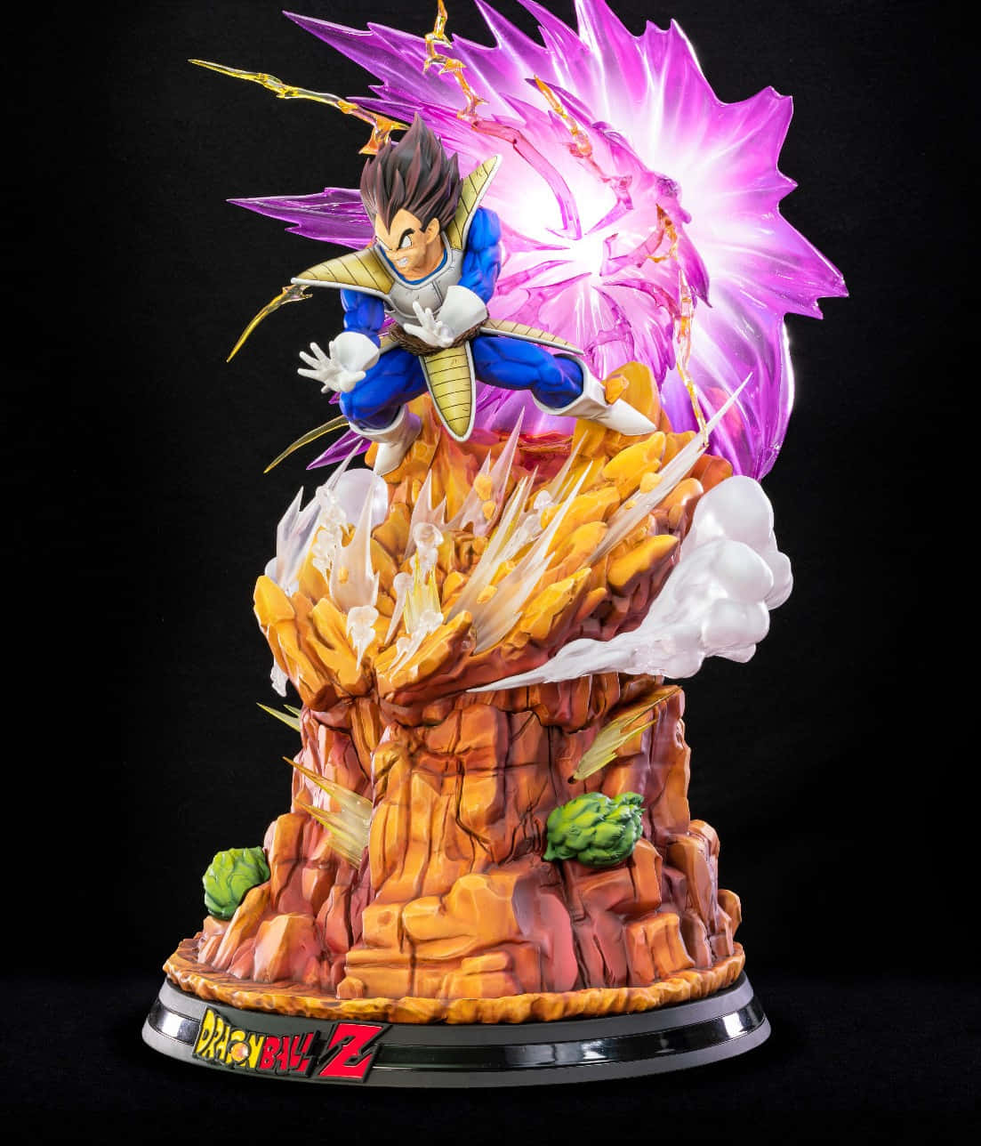 Vegeta Galick Gun 桌布 壁紙 — 一個詳細的達爾超級賽亞人形態雕像，在帶有七龍珠Z標誌的岩石底座上釋放紫色能量爆炸。