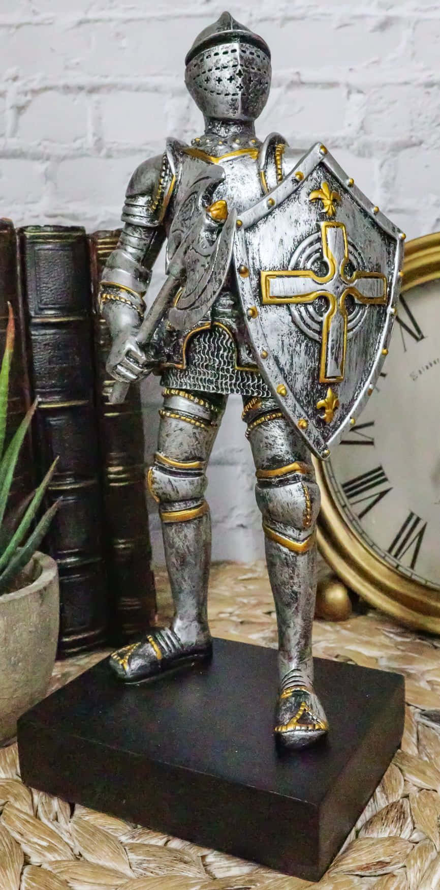 Crusader 桌布 壁紙 — 一個詳細的銀色和金色騎士雕像，身穿全套盔甲，自豪地站在黑色底座上，旁邊是復古書籍和一個時鐘。