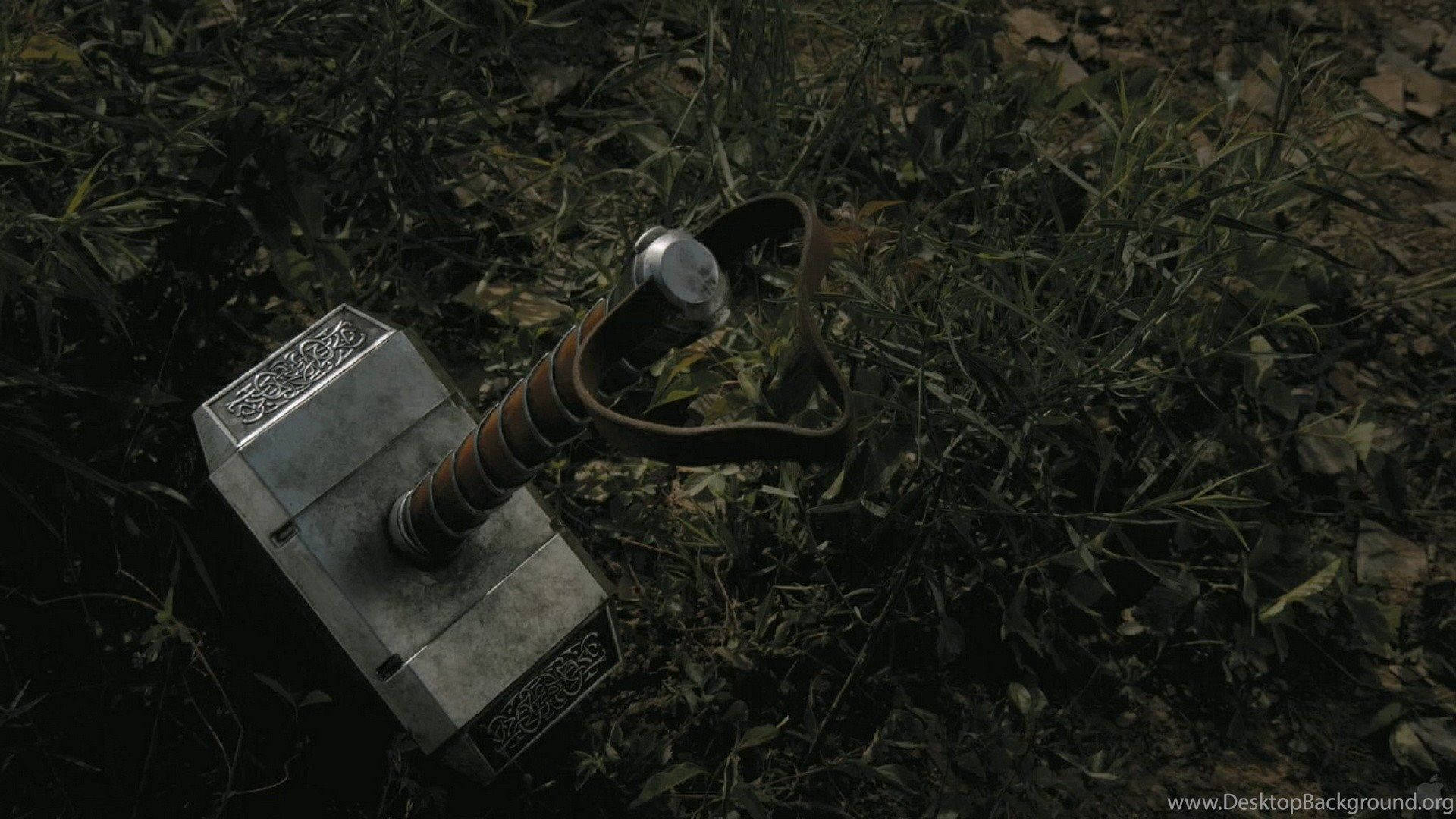 Thor Hammer 桌布 壁紙 — 一個詳細的雷神之鎚嵌在昏暗燈光下的深色樹葉中。