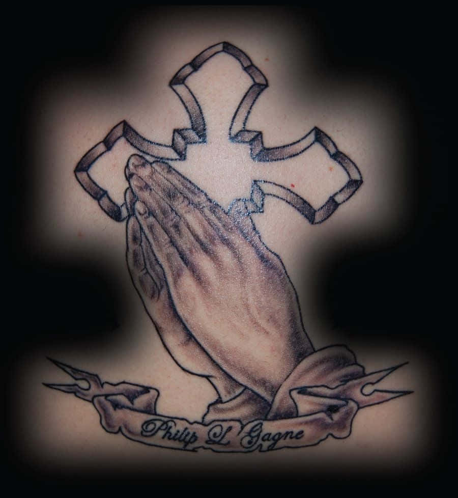 Praying 桌布 壁紙 — 一個詳細的黑灰色紋身，描繪十字架下方緊握的雙手，並帶有寫著 Philip L Gagne 的橫幅。