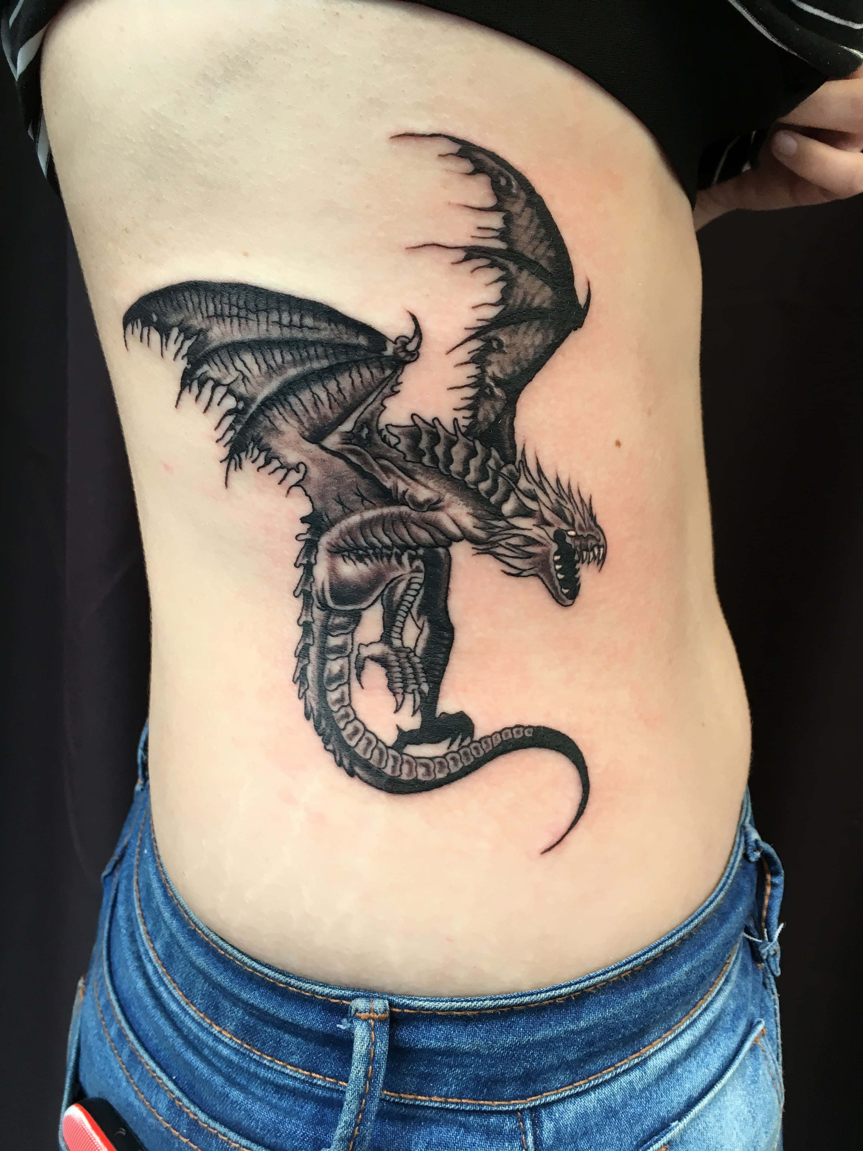 Fantasy Art Tattoo 桌布 壁紙 — 一個詳細的黑灰色龍紋身，張開翅膀，尖銳牙齒，裝飾在一個人的側面。