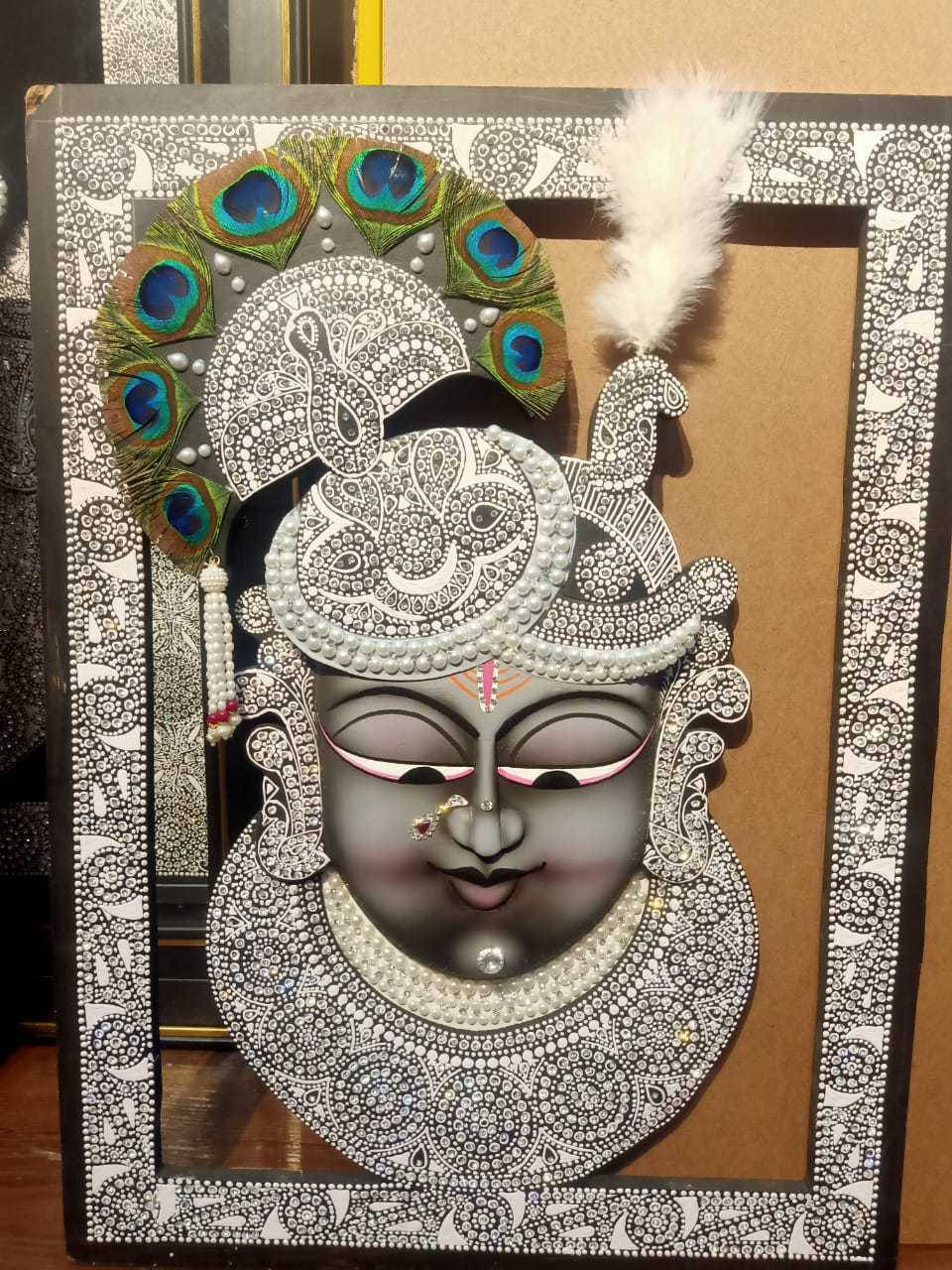 Shrinathji 桌布 壁紙 — 一個詳細的黑白點畫神祇面具，飾有孔雀羽毛和珍珠，鑲嵌在華麗圖案中。