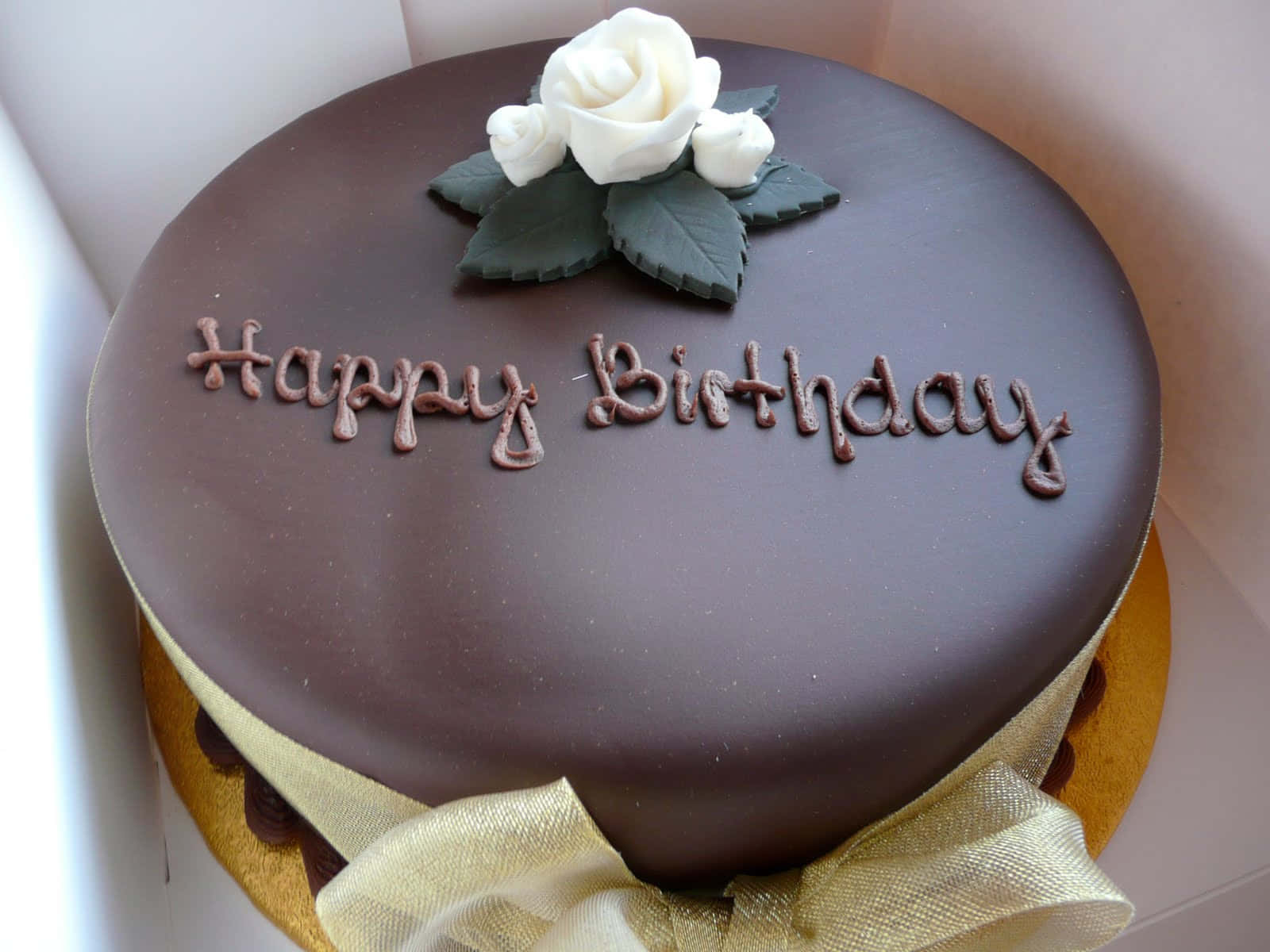 Happy Birthday Cake 桌布 壁紙 — 一個豐富的巧克力生日蛋糕，上面有白玫瑰和糖霜字樣，放在禮物盒中。