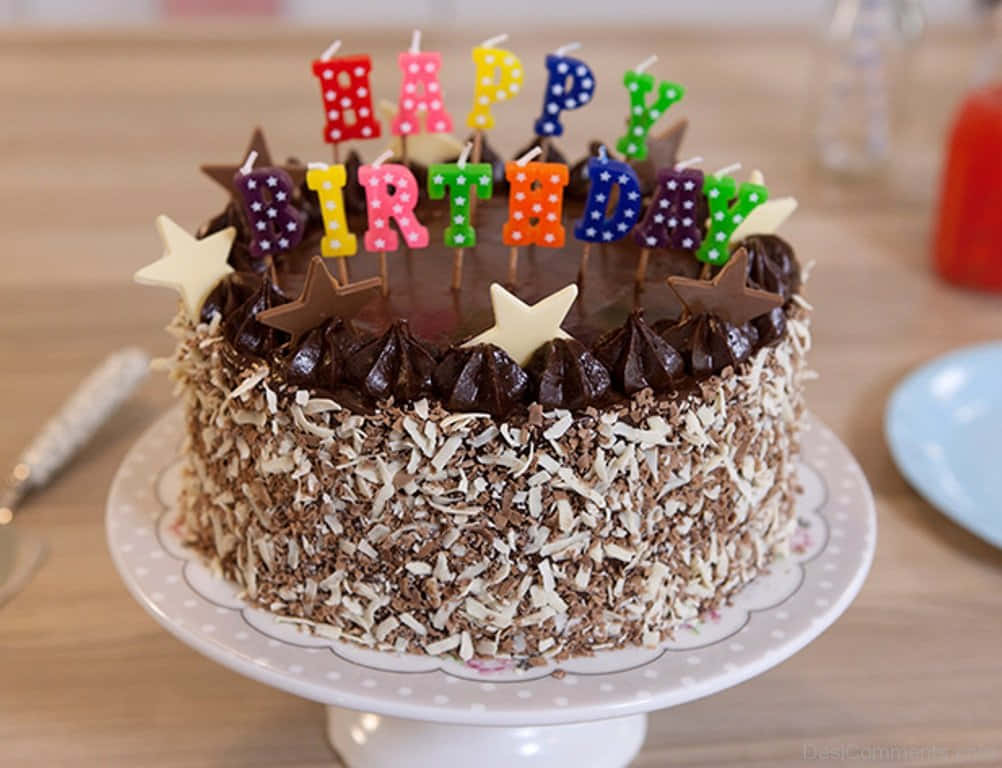 Birthday Cakes 桌布 壁紙 — 一個豐富的巧克力生日蛋糕，飾有拼出 happy birthday 的彩色字母蠟燭和星星裝飾。