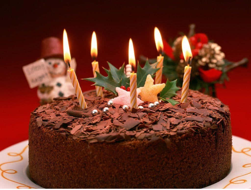 Chocolate Cake 桌布 壁紙 — 一個豐富的巧克力蛋糕，上面放著點燃的蠟燭、冬青漿果和銀色珠子，背景是節日的紅色。