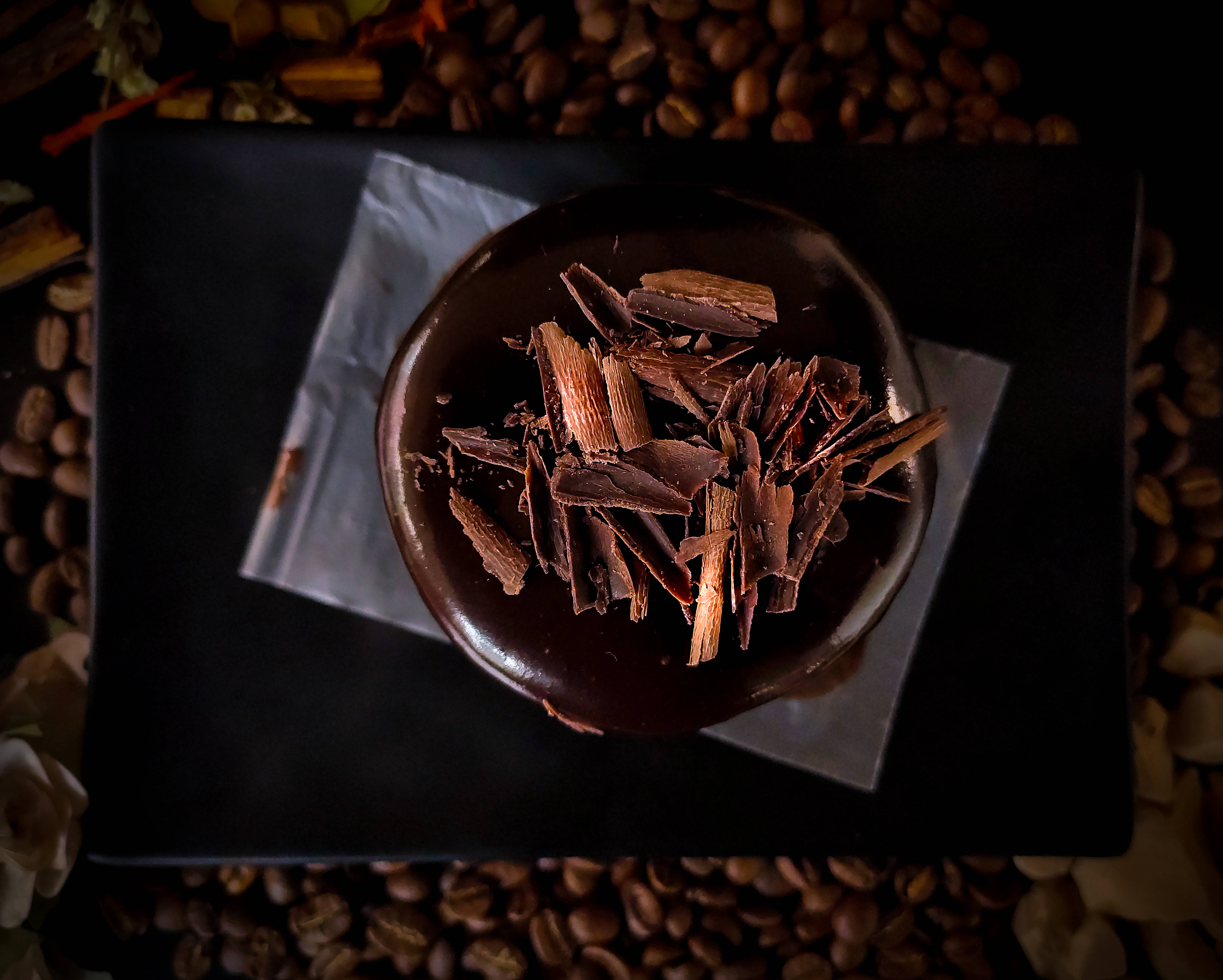 Chocolate 桌布 壁紙 — 一個豐富的巧克力蛋糕，上面有黑巧克力碎，放在一個被咖啡豆包圍的黑色盤子上。