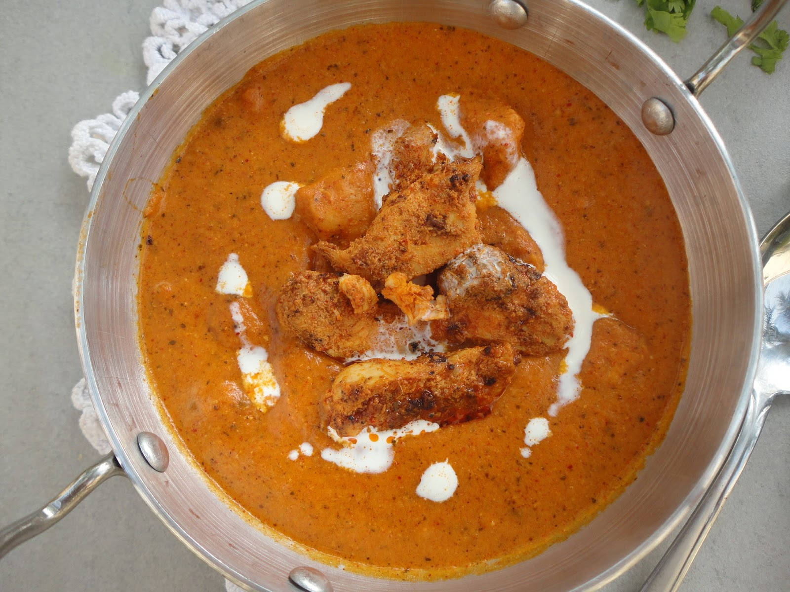 Chicken 桌布 壁紙 — 一個豐富的橙色雞肉咖哩，帶有奶油白色漩渦，放在不鏽鋼鍋中的蕾絲墊上。
