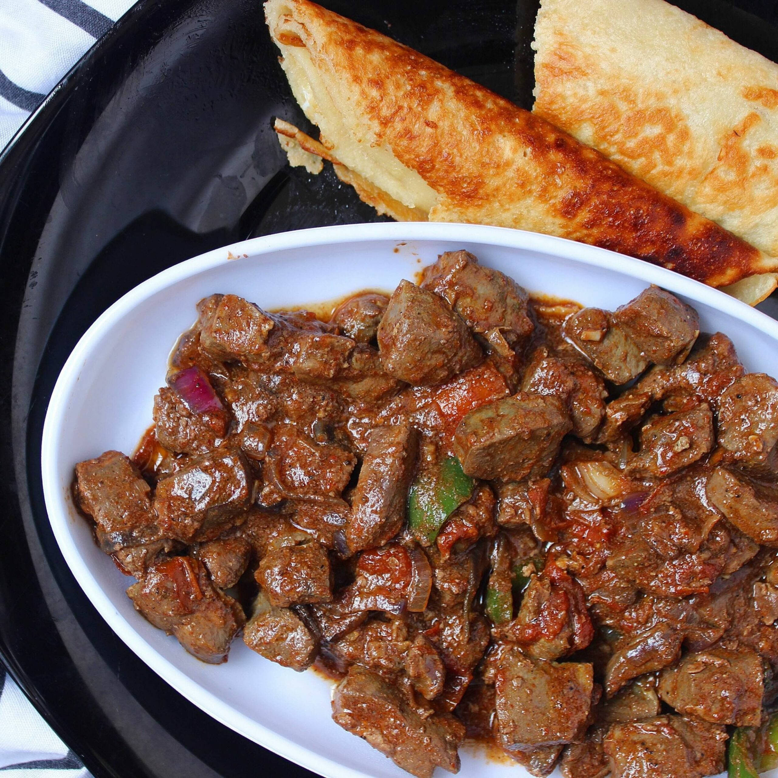 meat 桌布 壁紙 — 一個豐富香料調味的肉咖哩，配以色彩繽紛的甜椒和洋蔥，盛載於白色碗中，與金黃色的印度烤餅一同放在黑色托盤上。