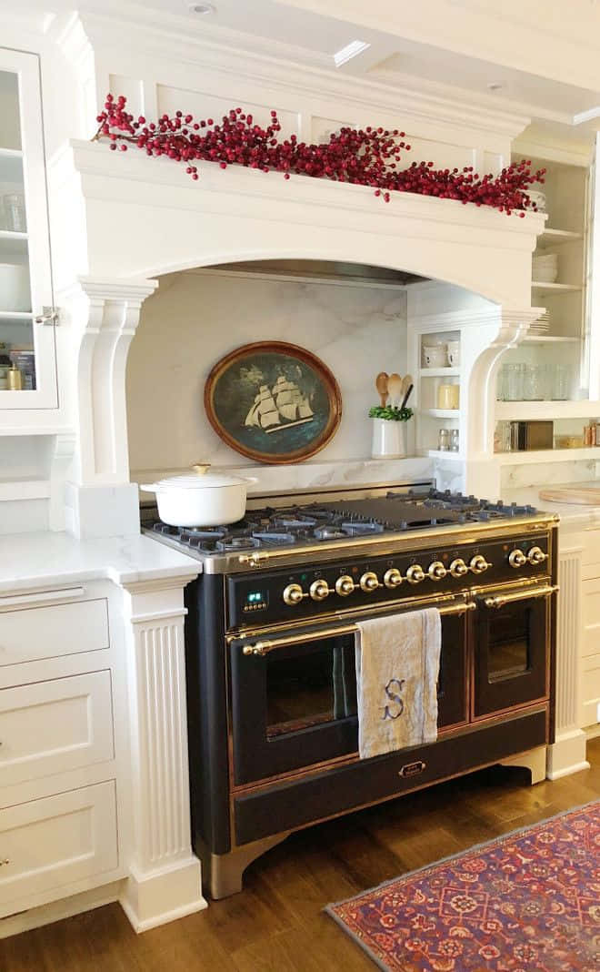 Stove 桌布 壁紙 — 一個豪華廚房，黑色黃銅爐灶下方是白色壁爐架，裝飾著紅色漿果和船畫。