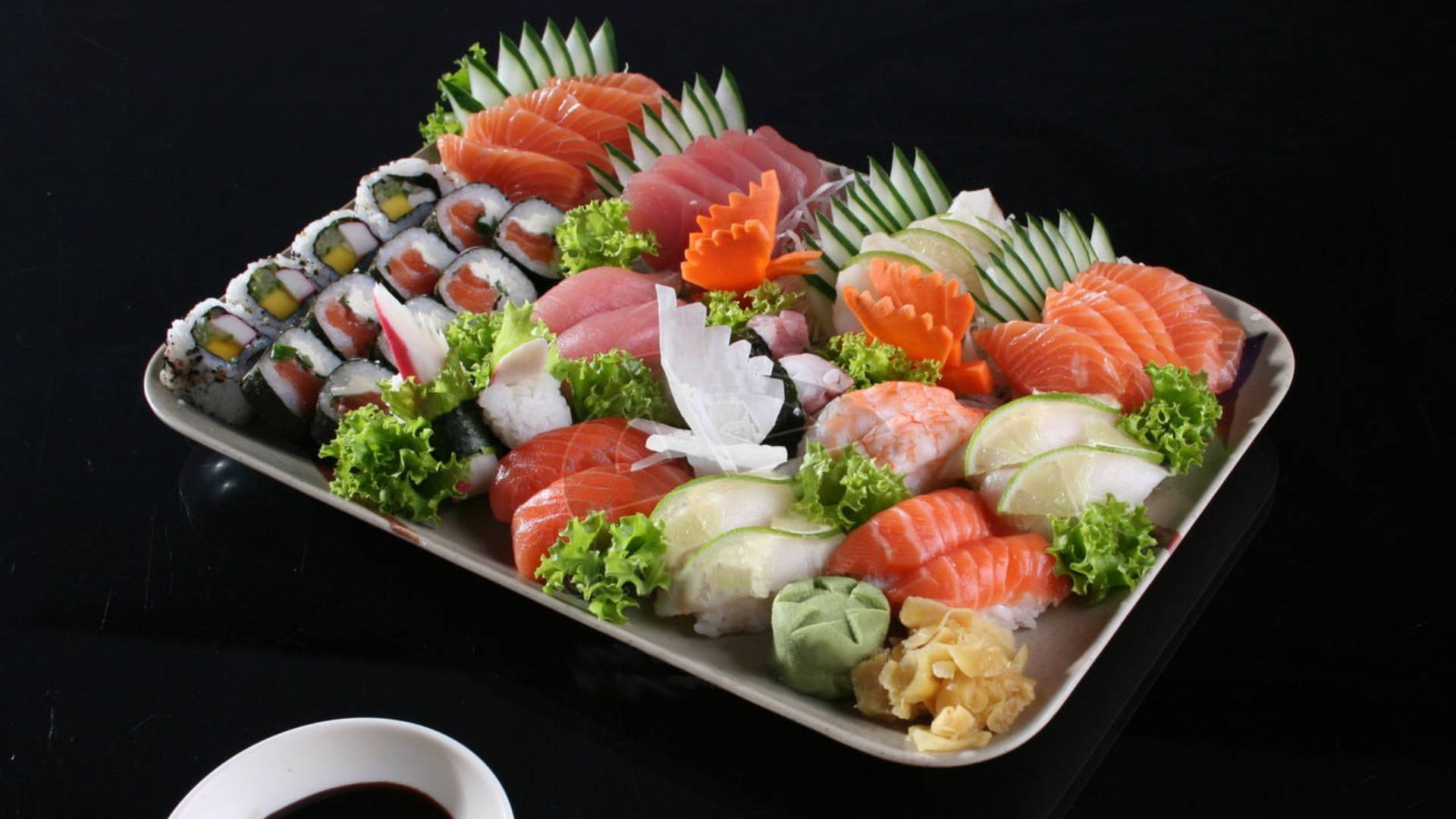 Sushi 桌布 壁紙 — 一個豪華的拼盤，上面有各種壽司和生魚片，在深色表面上配以裝飾藝術地擺放。