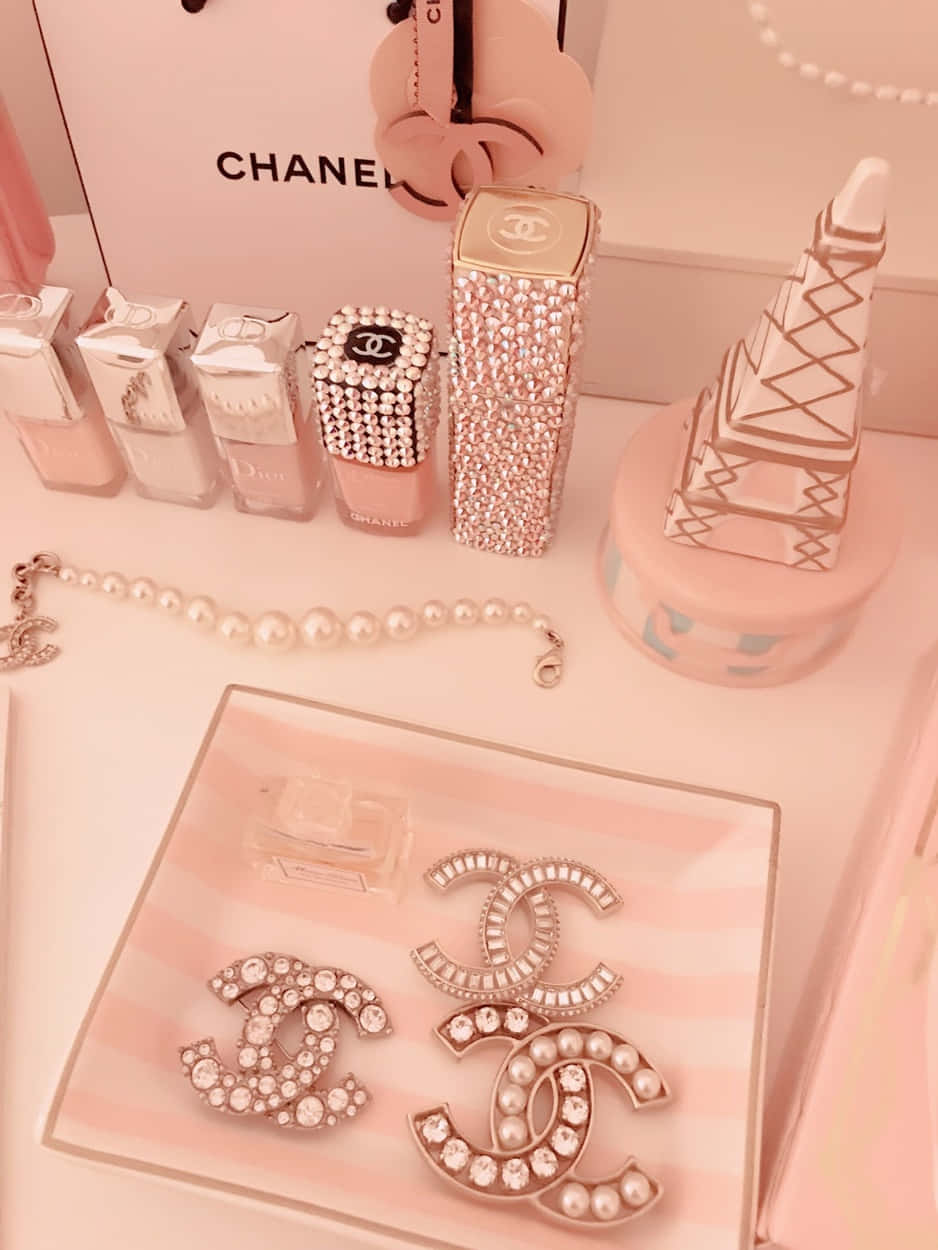 Chanel Aesthetic 桌布 壁紙 — 一個豪華的粉紅色香奈兒主題梳妝台展示，配有閃亮的標誌珠寶、指甲油和微型艾菲爾鐵塔。
