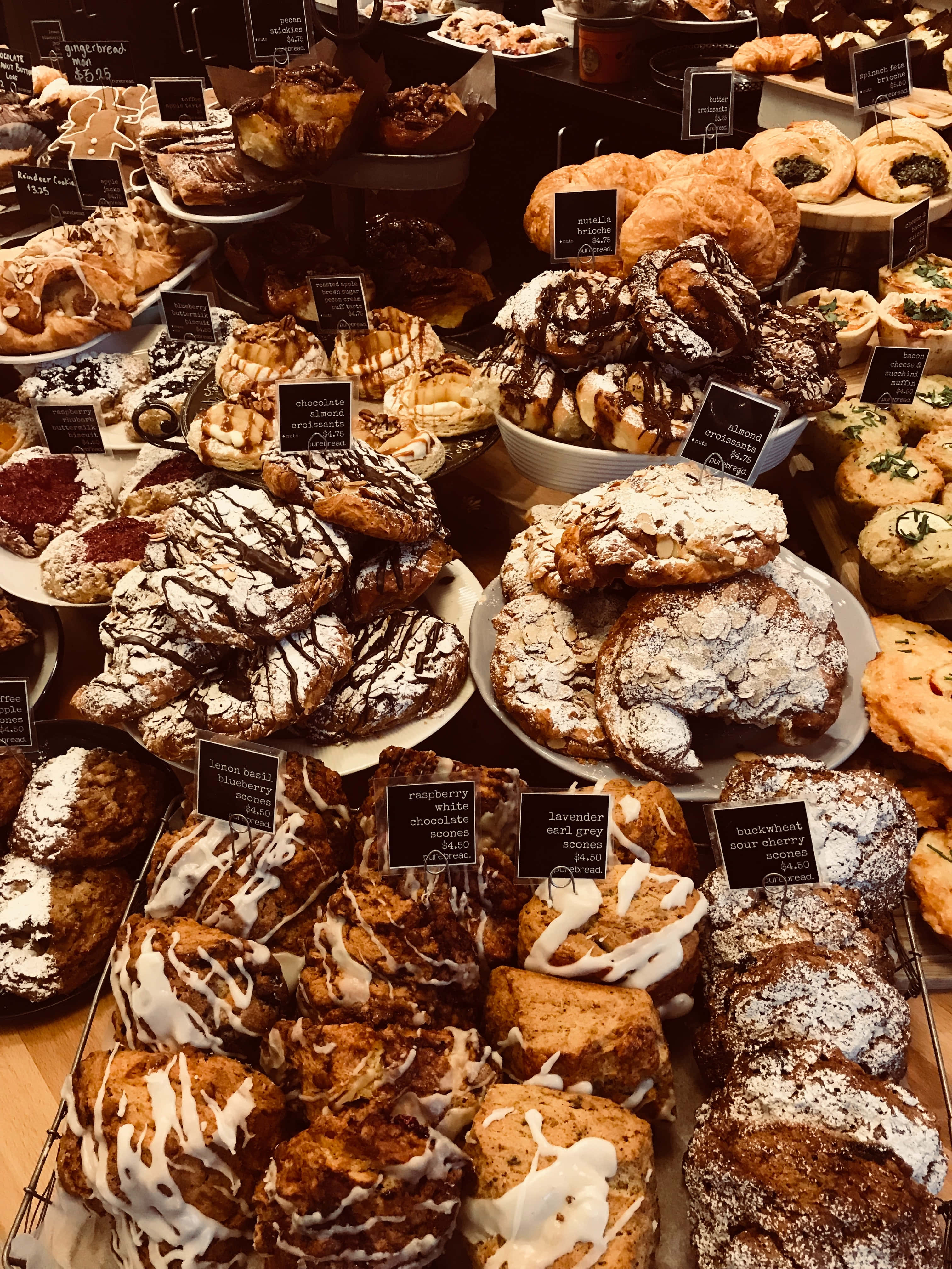 Bakery 桌布 壁紙 — 一個豪華的麵包店展示櫃，堆滿了淋上巧克力和糖霜的各式糕點。