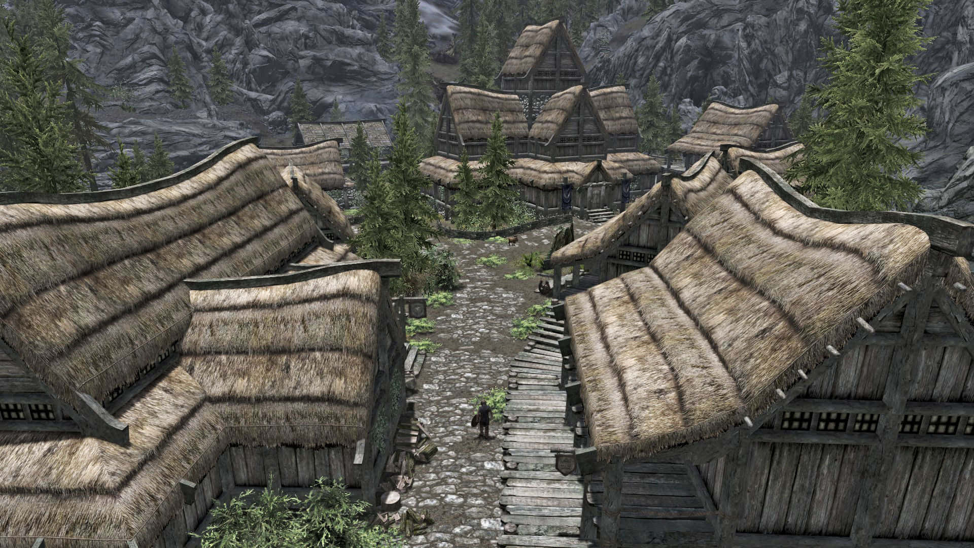 Skyrim Falkreath 桌布 壁紙 — 一個質樸的中世紀村莊，茅草屋頂的小屋坐落在森林覆蓋的山谷中。