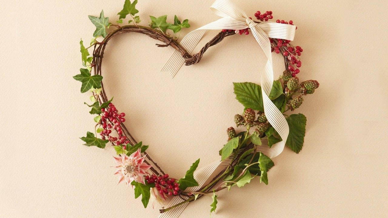 Cute Heart 桌布 壁紙 — 一個質樸的心形花環，飾有常春藤、紅色漿果和奶油色絲帶，背景是柔和的米色牆壁。