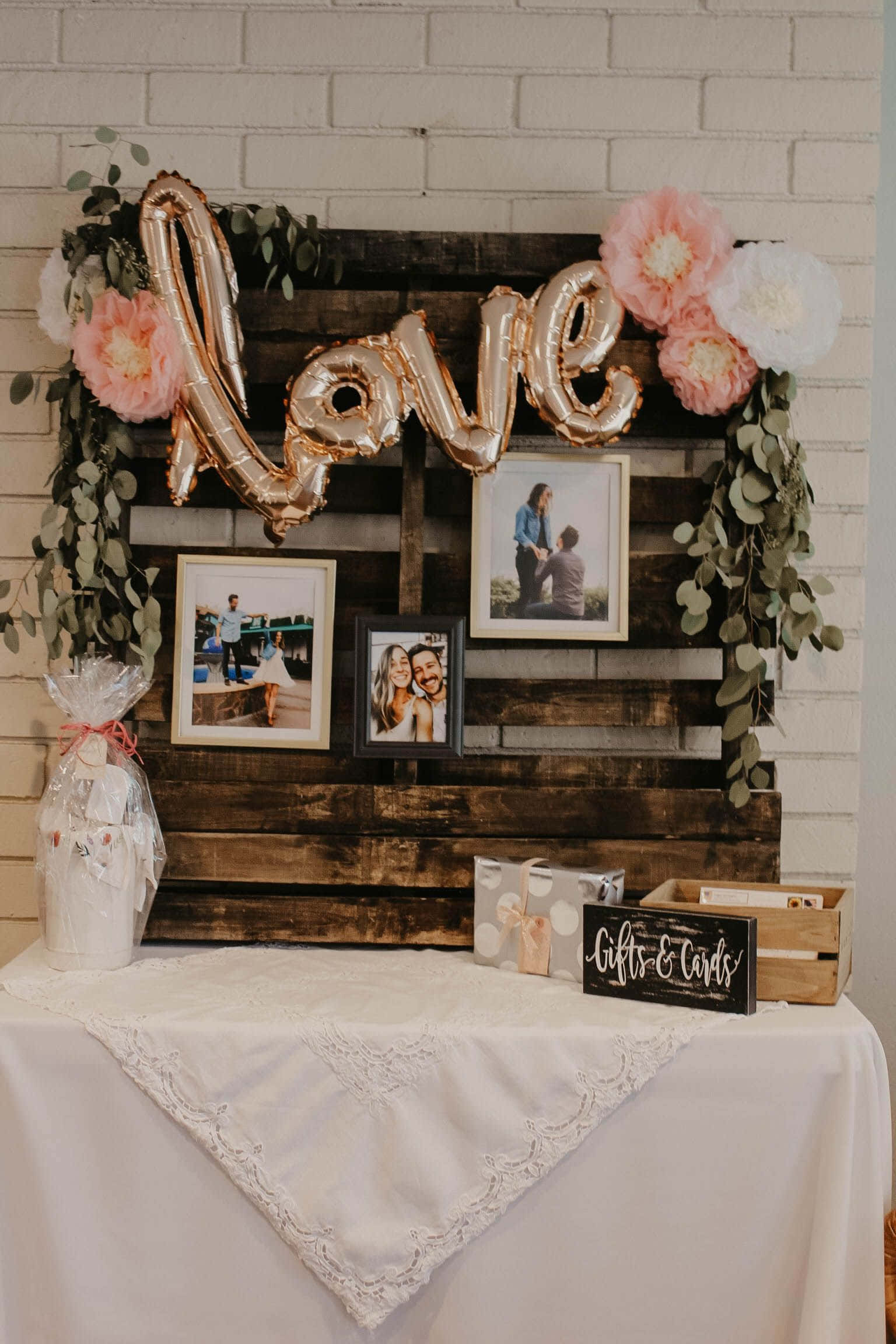 Wedding 桌布 壁紙 — 一個質樸的木托盤背景，裝飾著玫瑰金 'love' 氣球、粉紅色和白色的花朵，以及裱框的情侶照片，適合婚禮或週年慶祝活動。