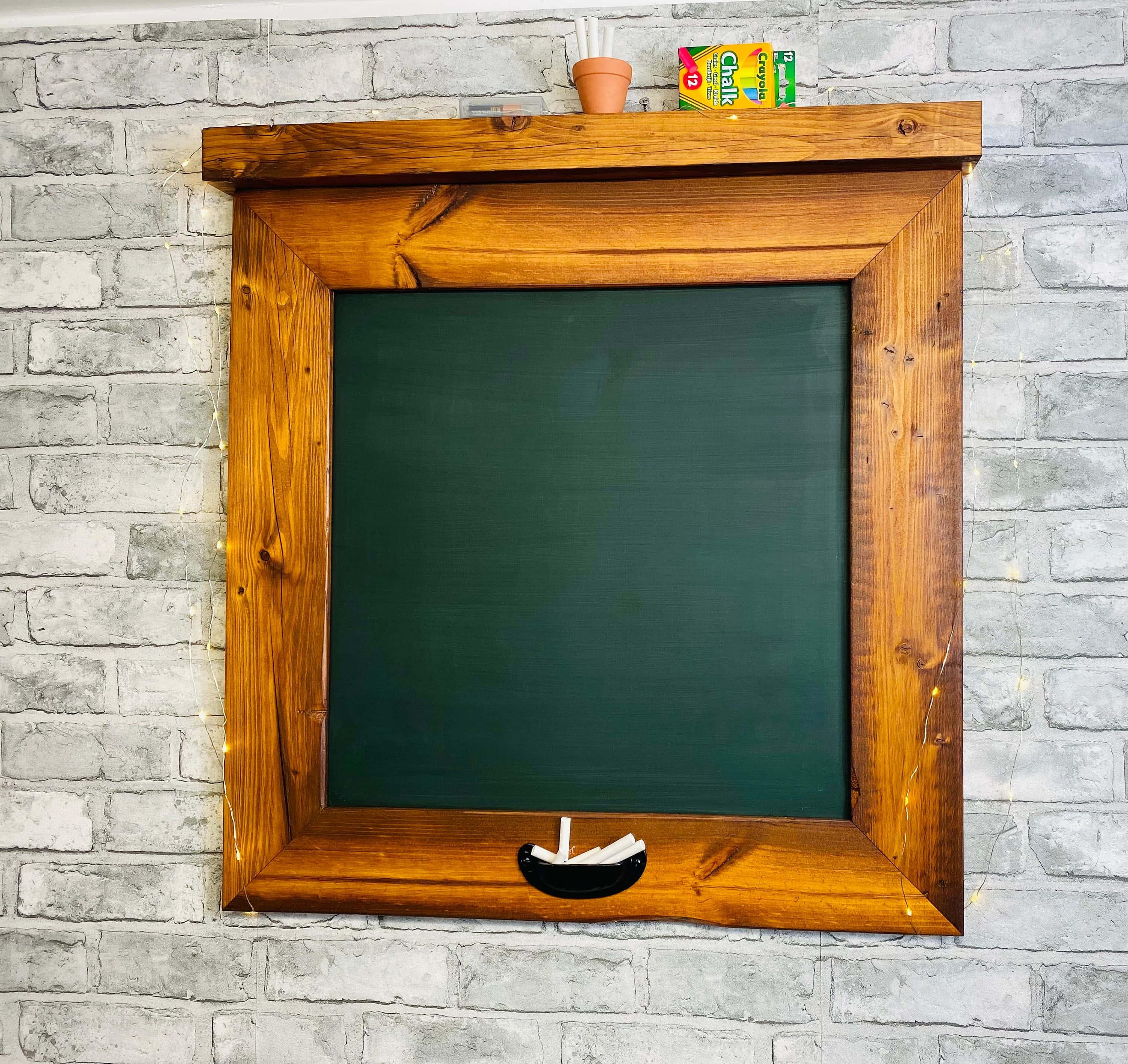 Green Chalkboard 桌布 壁紙 — 一個質樸的木框黑板安裝在灰色磚牆上，下方有仙女燈和小船裝飾。