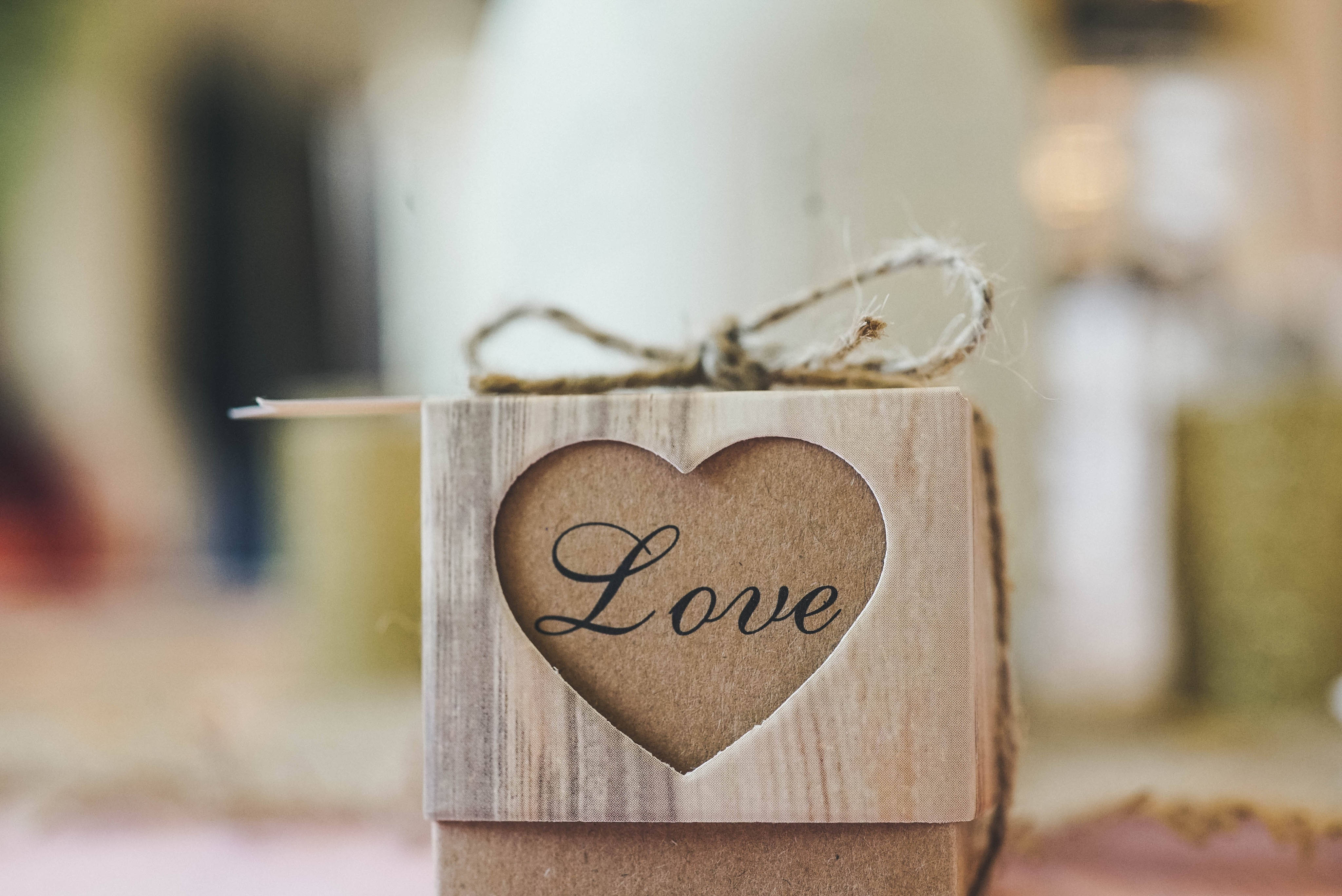 愛心 桌布 壁紙 — 一個質樸的木盒，心形鏤空露出草書的「Love」字樣，用麻繩繫著。
