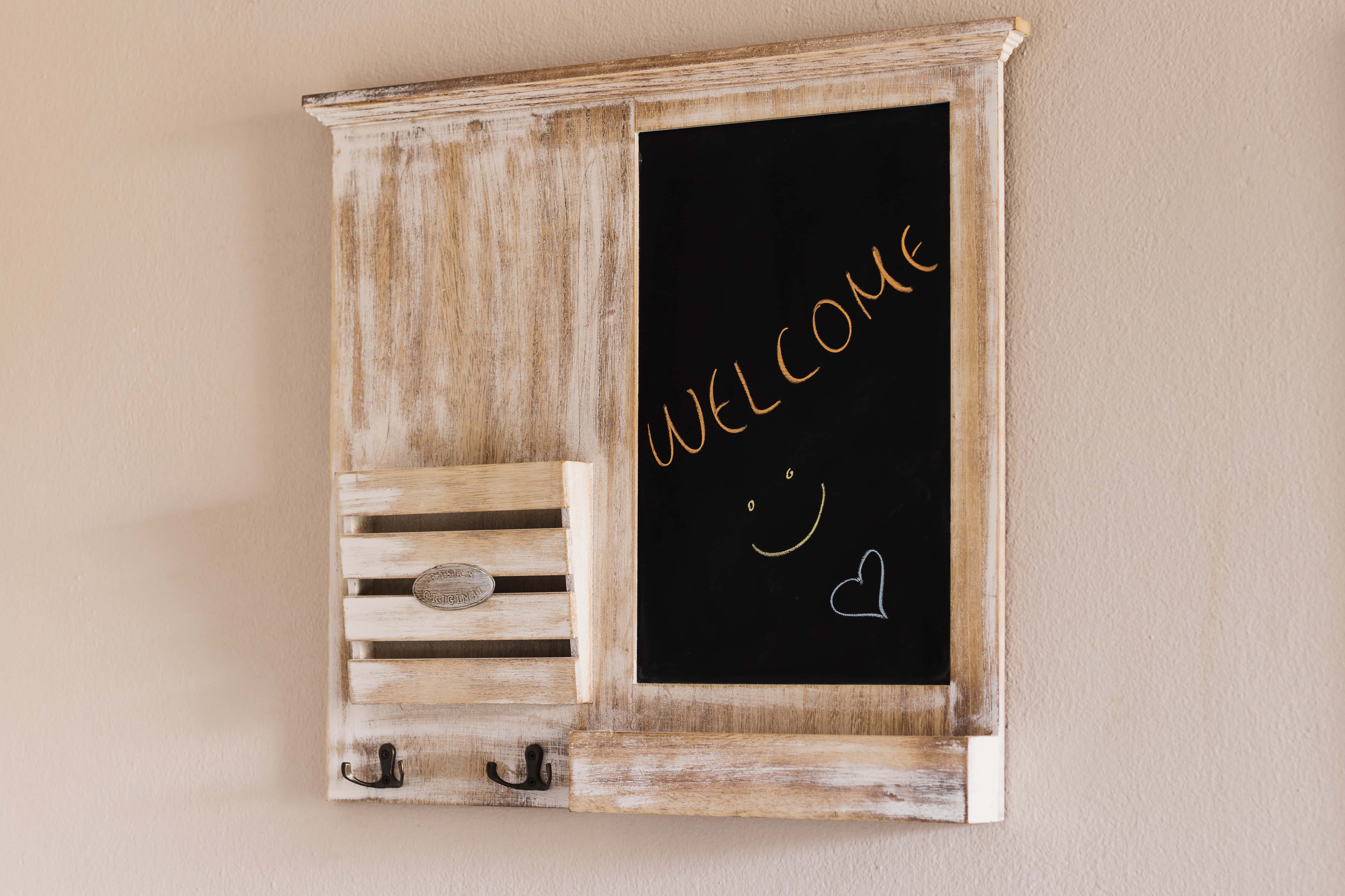 Welcome 桌布 壁紙 — 一個質樸的木製壁掛黑板，上面用粉筆寫著「WELCOME」和笑臉，配有掛鉤和板條抽屜。