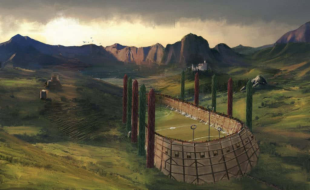 The Hogwarts Quidditch Pitch 桌布 壁紙 — 一個質樸的木製體育館坐落於廣闊的綠色山谷中，遠山在戲劇性的多雲天空下。