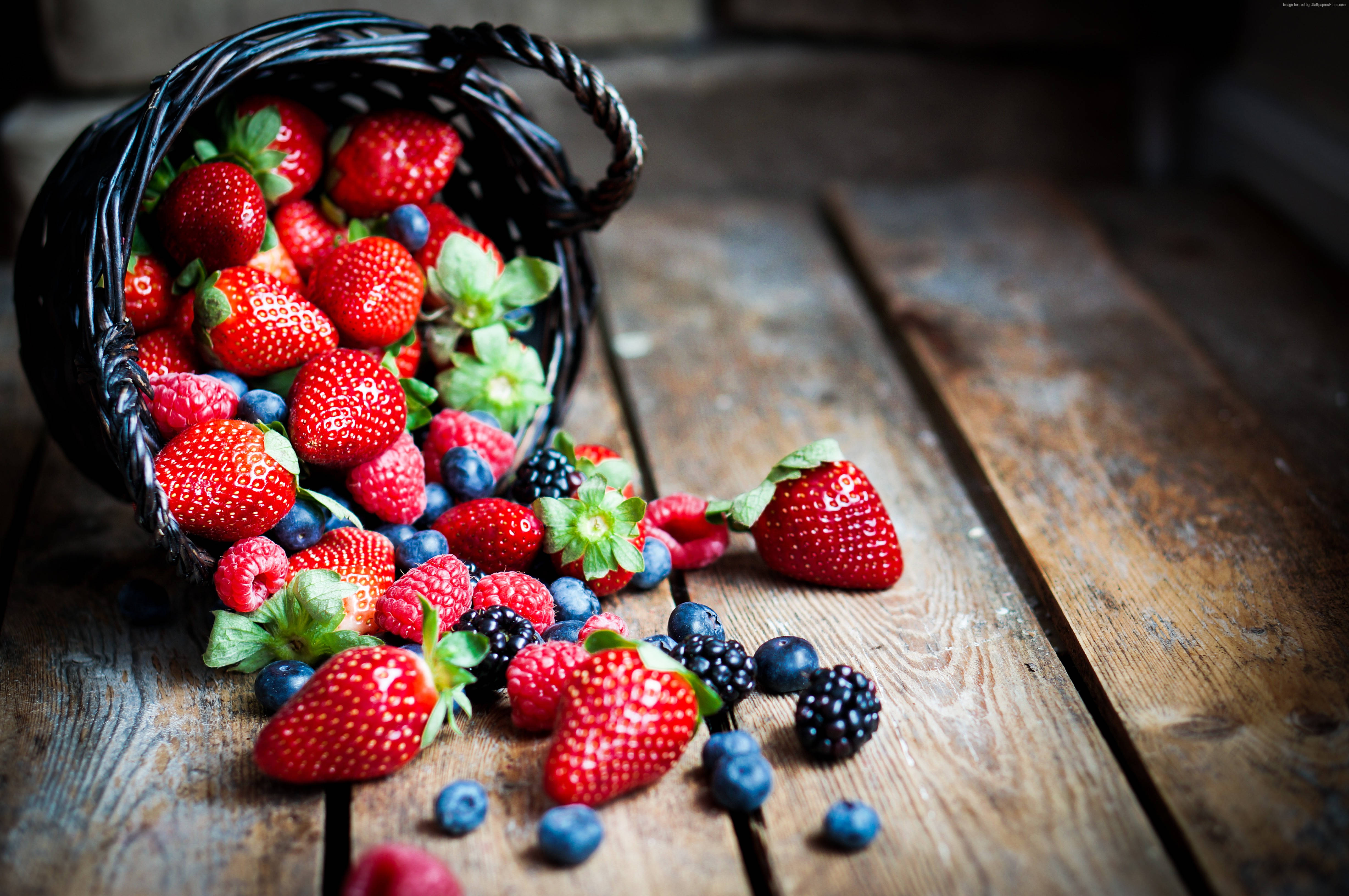 Fruit 桌布 壁紙 — 一個質樸的柳條籃子將鮮紅色的草莓、覆盆子、藍莓和黑莓灑在一個經風化的木桌上。