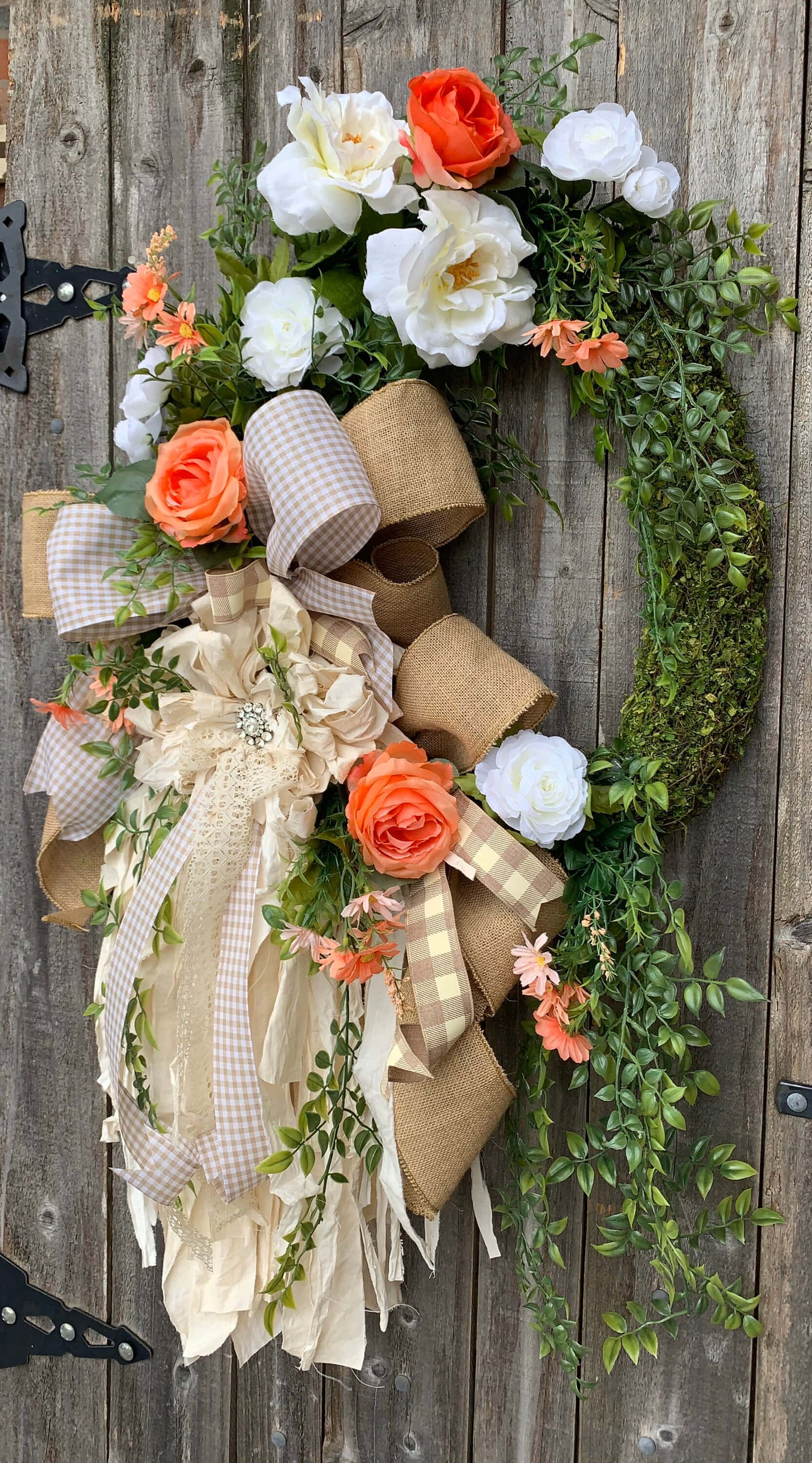 Spring Wreaths 桌布 壁紙 — 一個質樸的花環，飾有橙色和白色的玫瑰、綠葉和麻布蝴蝶結，掛在風化的木門上。