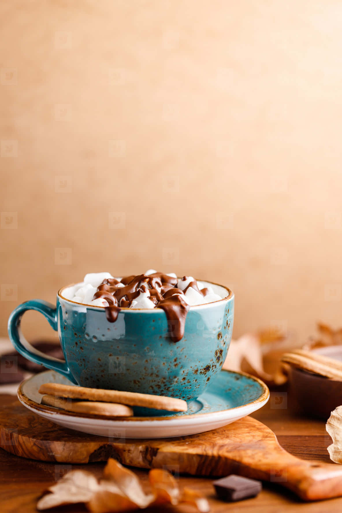 Hot Chocolate 桌布 壁紙 — 一個質樸的藍色陶瓷杯裝滿熱巧克力，上面加上鮮奶油和巧克力醬，放在木板上，周圍有秋葉和餅乾。