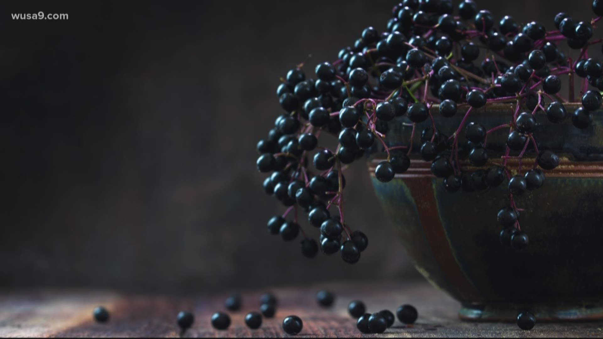Fruits 桌布 壁紙 — 一個質樸的陶瓷碗裝滿了光澤的黑接骨木漿果，溢出到風化的木質表面上，在柔和昏暗的燈光下。