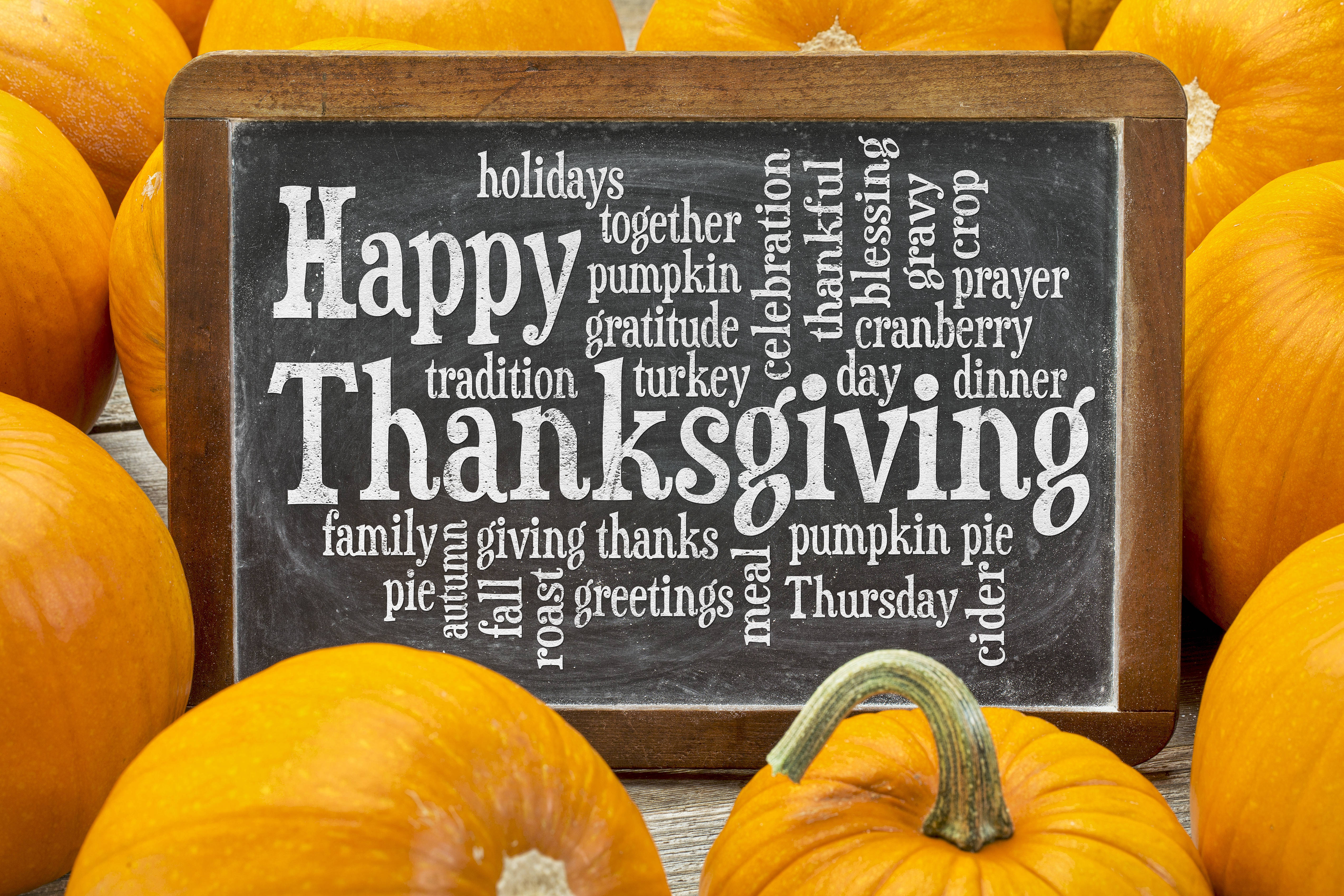 可愛感恩節 桌布 壁紙 — 一個質樸的黑板，上面寫著「Happy Thanksgiving」，周圍環繞著鮮豔的橙色南瓜，放在木質表面上。