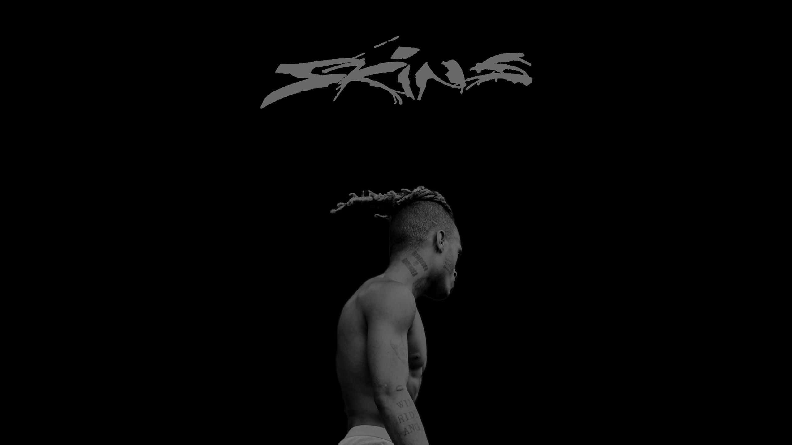 XXXTENTACION 桌布 壁紙 — 一個赤膊、留著辮子頭的男人側面站在黑色背景前，上方有風格化的文字「Skins」。