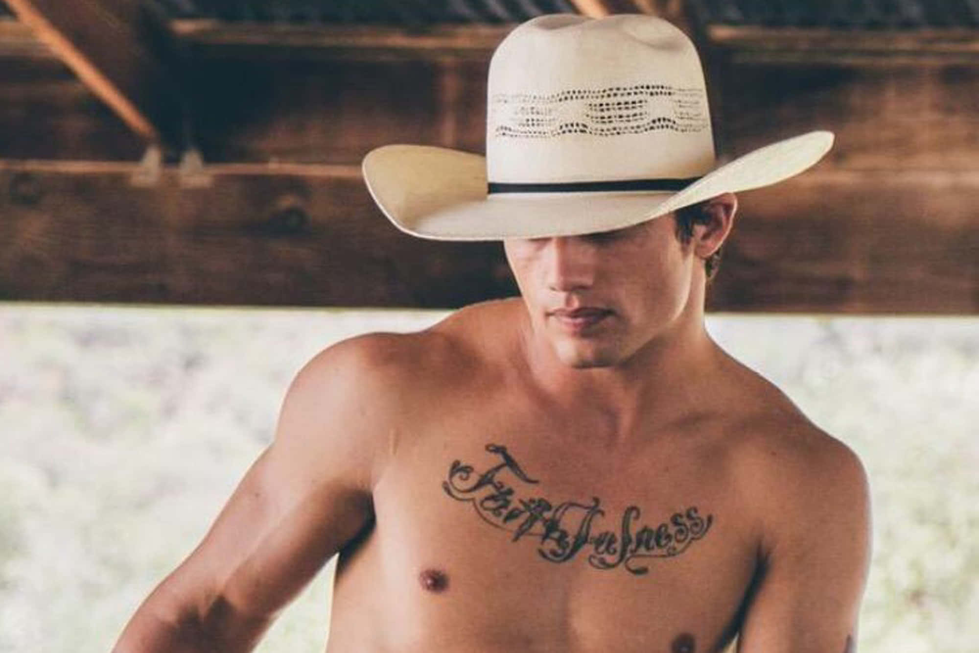 Bull Rider 桌布 壁紙 — 一個赤膊戴牛仔帽的男人向下看，胸前有刺青寫著「Faithfulness」，身處木樑下。