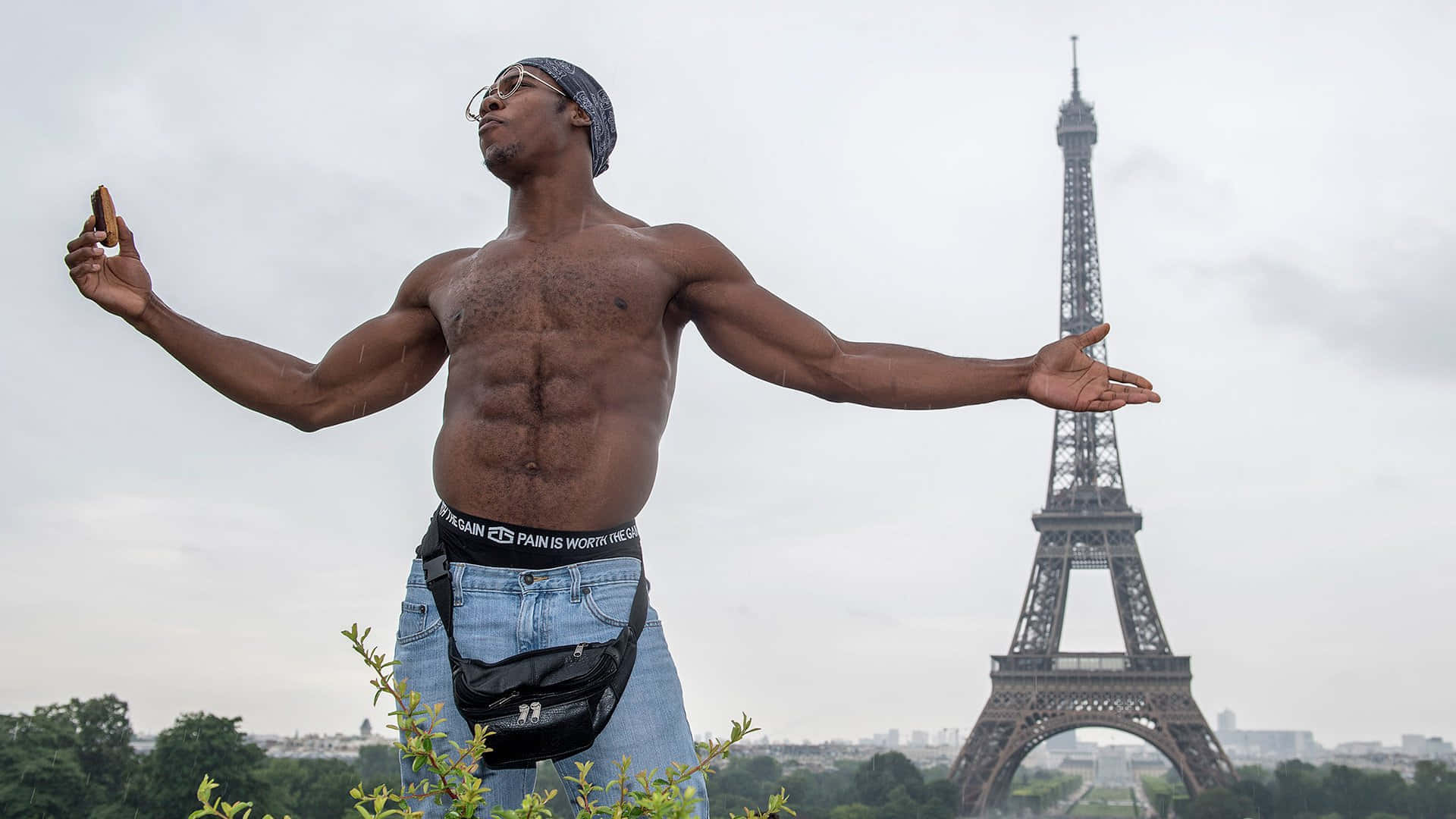 WWE 桌布 壁紙 — 一個赤膊的肌肉男在陰天張開雙臂，勝利地站在艾菲爾鐵塔前。