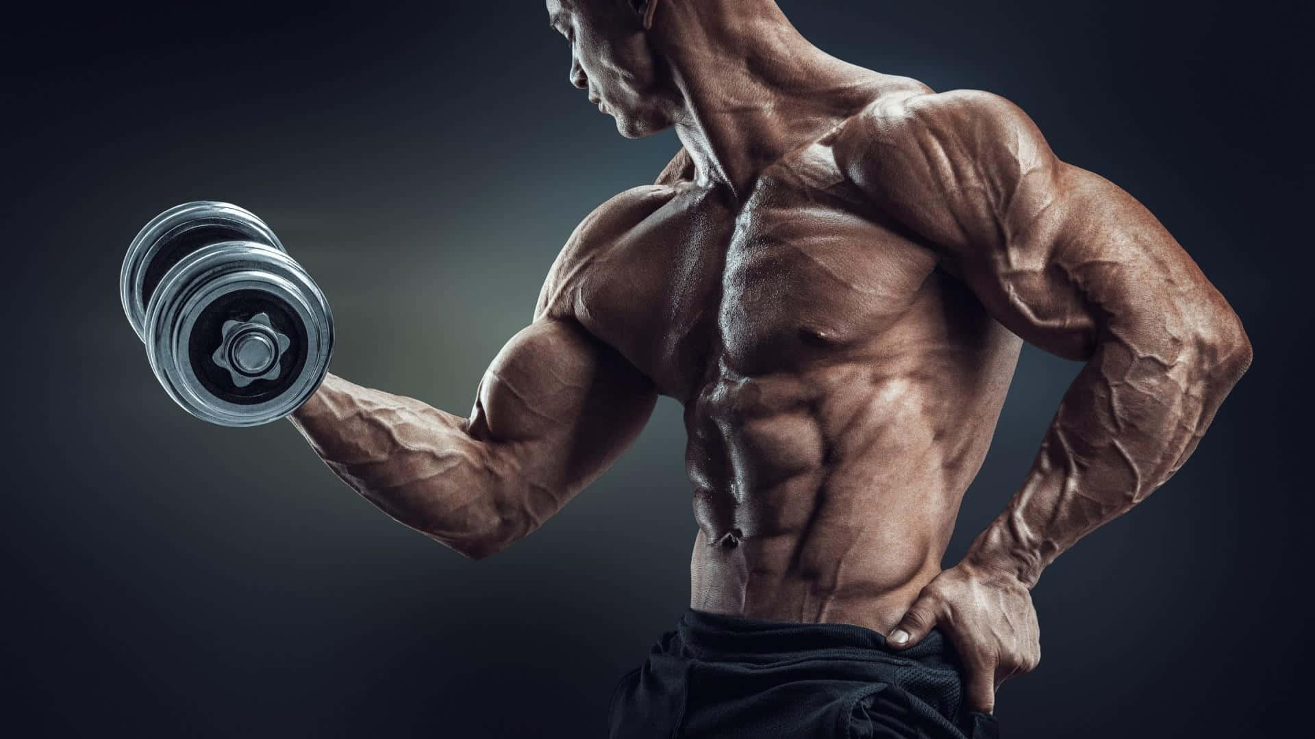 Workout 桌布 壁紙 — 一個赤膊肌肉男在黑暗的攝影棚背景下，彎曲手臂舉起啞鈴。
