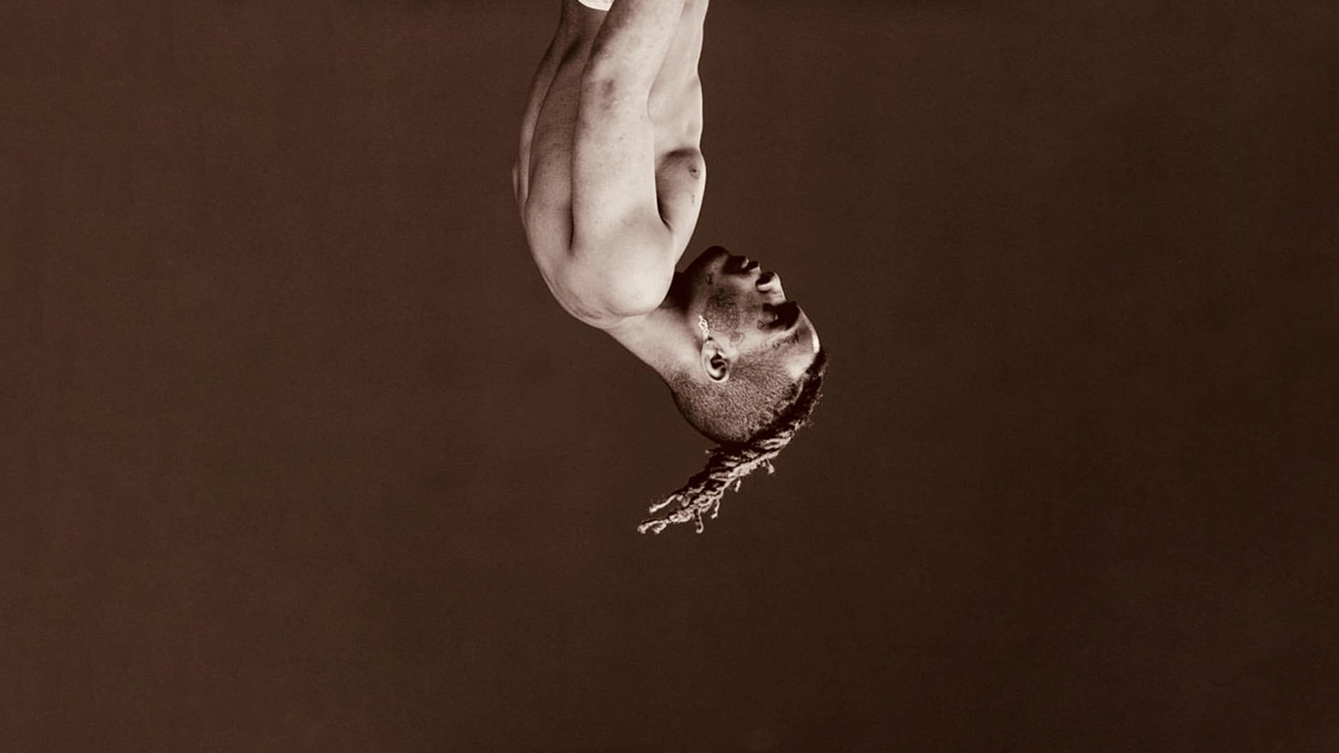 xxxtentacion 美學 桌布 壁紙 — 一個赤裸上身的男人倒掛在柔和的棕色背景上，頭向後傾斜，辮子向下流動。