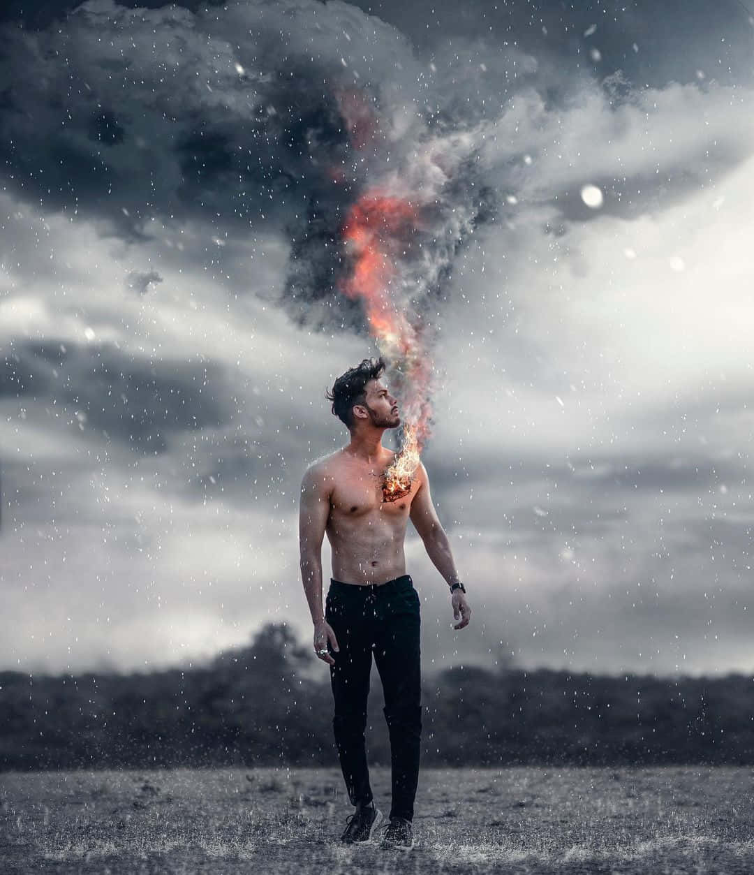 Vijay Mahar 桌布 壁紙 — 一個赤裸上身的男人站在暴風雨的田野中，對著陰暗多雲的天空從胸口呼出火焰般的煙霧。