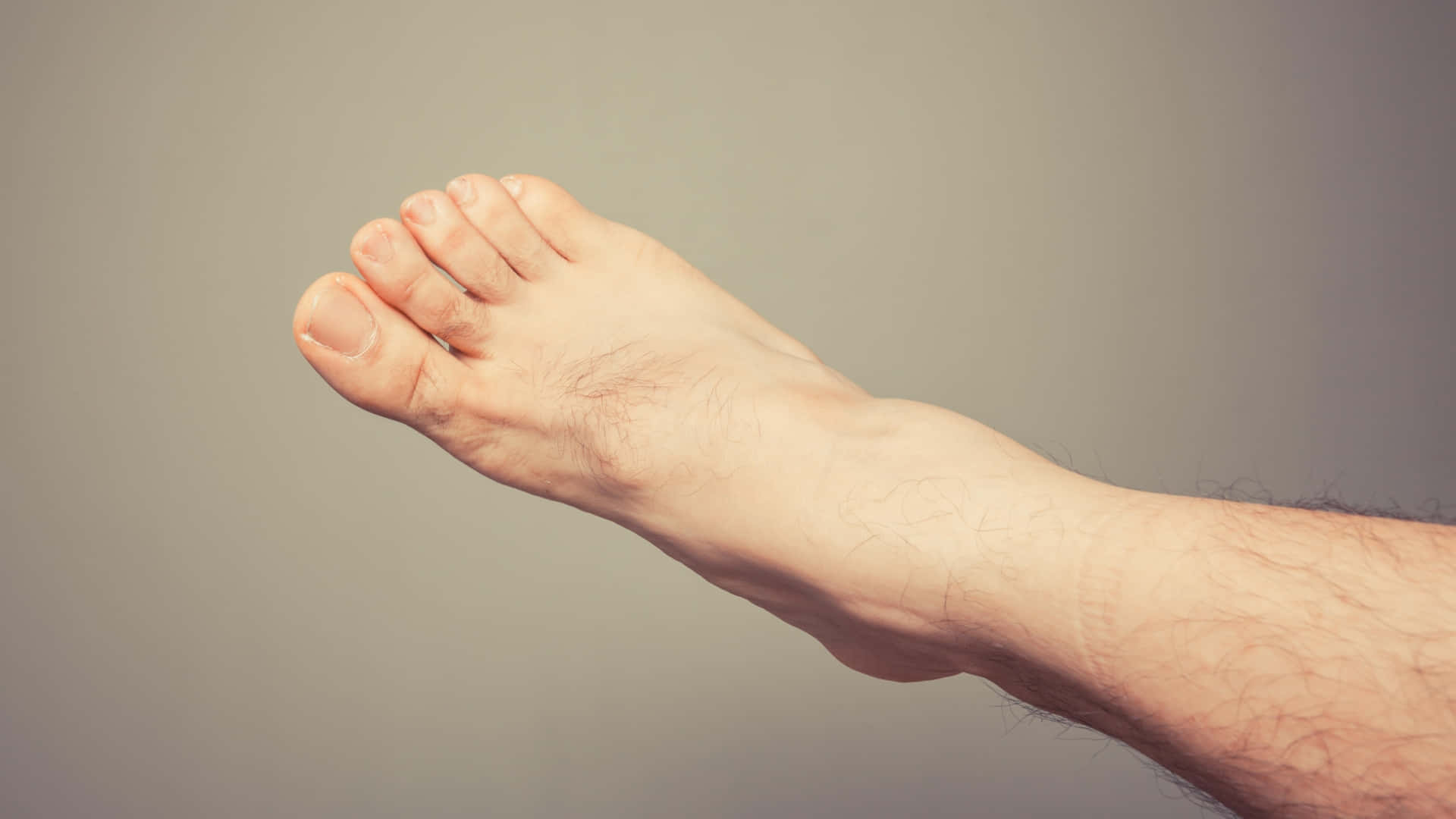 feet 桌布 壁紙 — 一個赤裸男性腳部及多毛腿部的特寫，背景為柔和灰色。