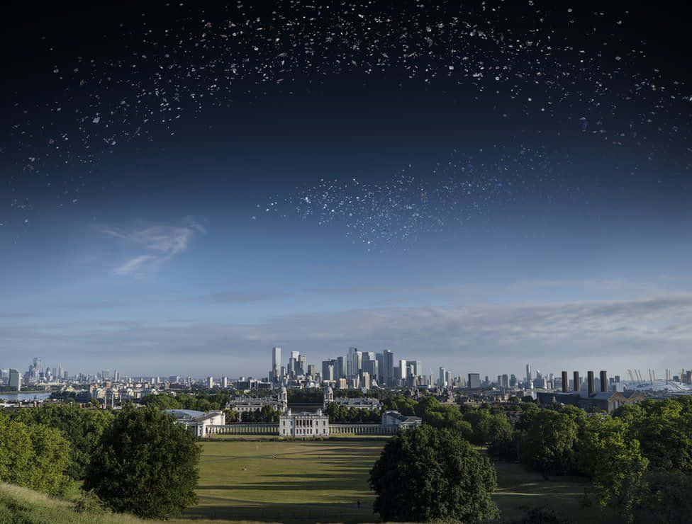 Space Debris 桌布 壁紙 — 一個超現實的城市景觀，繁星點點的夜空與綠色公園和現代摩天大樓上方的白天地平線融為一體。