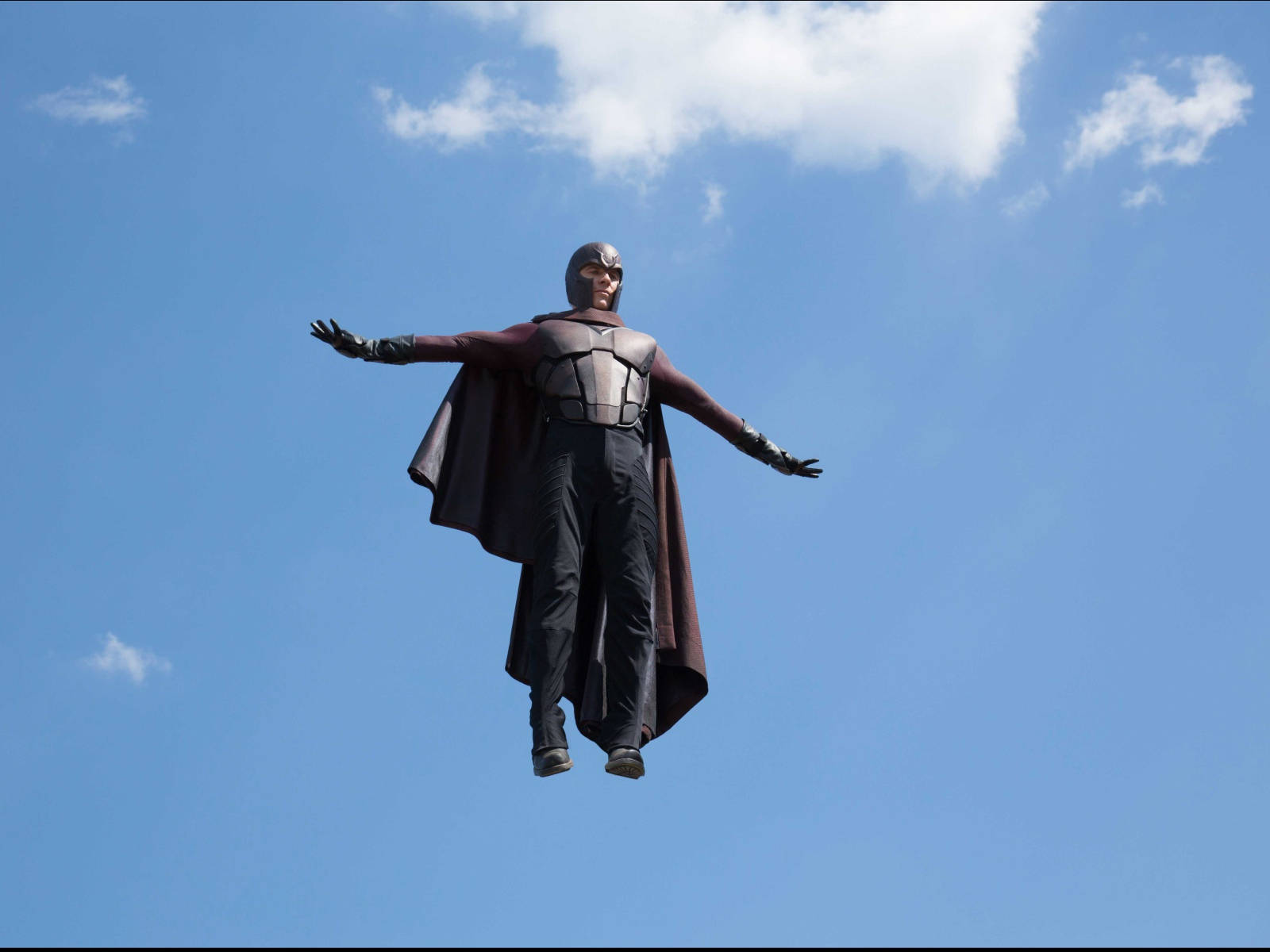 Magneto 桌布 壁紙 — 一個超級英雄雕像張開雙臂，漂浮在藍天白雲的背景中。