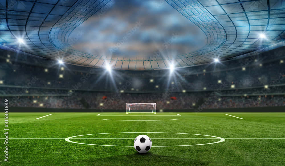 Soccer Stadium 桌布 壁紙 — 一個足球放在廣闊空蕩的體育場中央圓圈內，上方有明亮的泛光燈和多雲的天空。